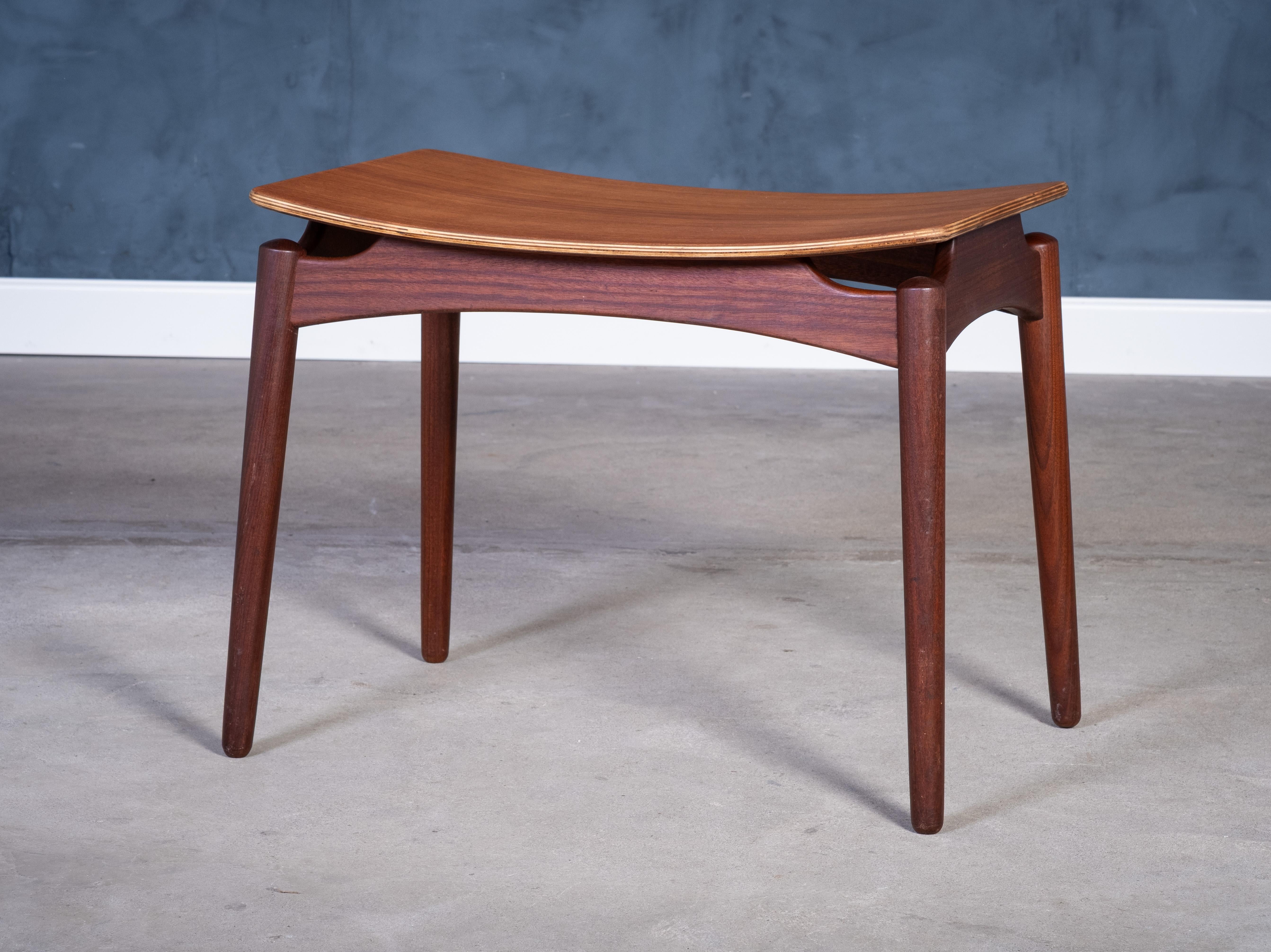Teak stool designed by Sigfred Omann and produced by Ølholm Møbelfabrik in the 1950s. Featuring a solid teak frame and a gracefully curved seat platform, this piece showcases the refined craftsmanship and timeless elegance of Danish mid-century