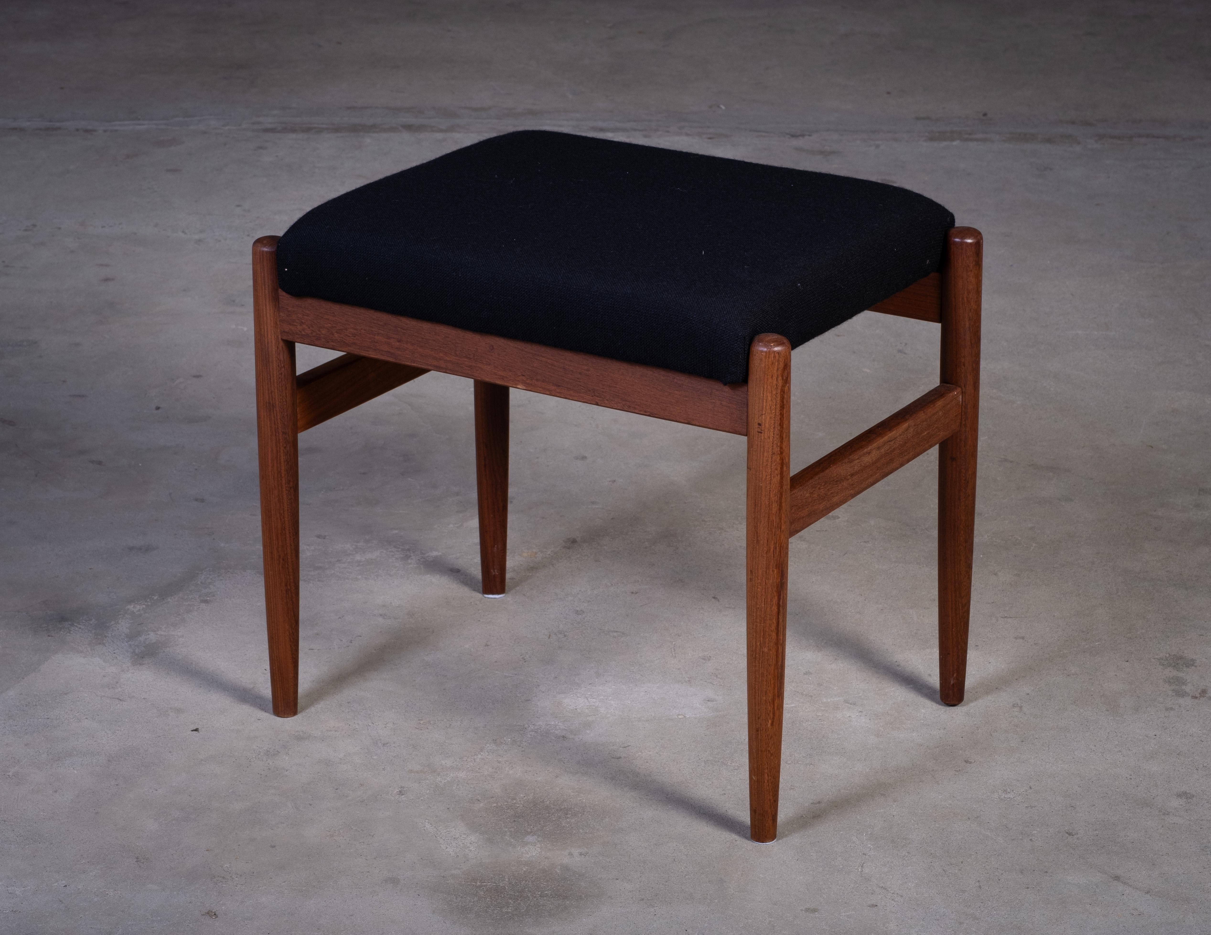 Elegant tabouret danois en teck des années 1960 avec une assise en tissu noir. Design/One simple et intemporel en bon état vintage avec des signes mineurs d'âge.

Nous laissons à nos clients le soin de décider s'ils souhaitent remettre les pièces à