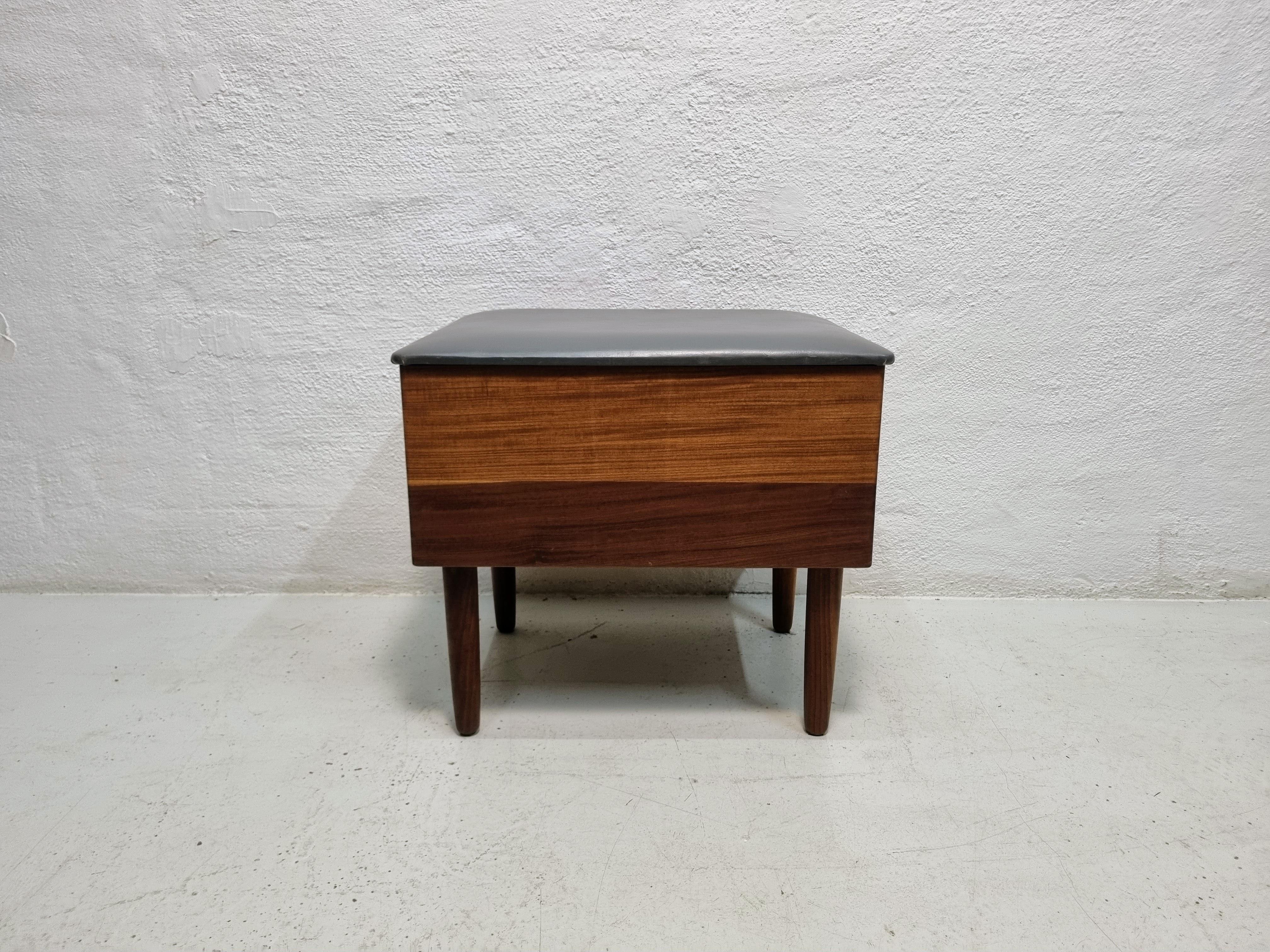 Teak stool with storage space under the seat.
Seat upholstered in gray artificial leather.