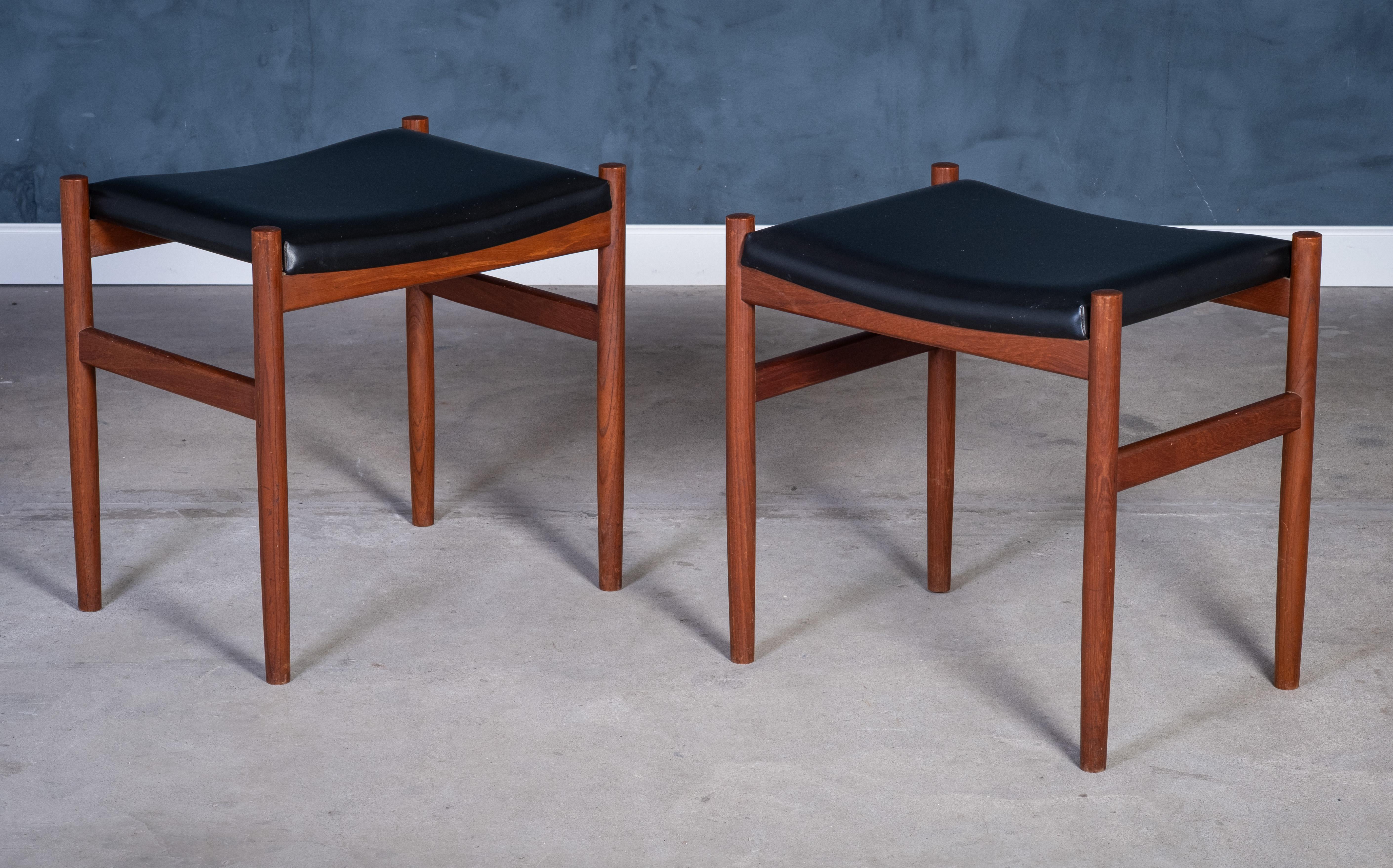 Elegantes Paar Teakholzhocker, hergestellt von der Spøttrup Møbelfabrik in den 1960er Jahren. Die mit schwarzem Leder bezogenen Hocker mit ihren schlanken Linien sind stilvoll und vielseitig einsetzbar - als zusätzliche Sitzgelegenheit, Fußstütze