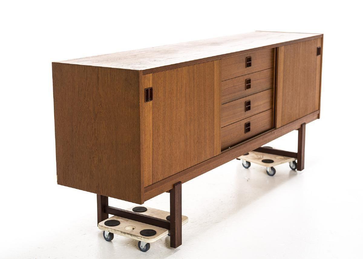 Teak Swedish mid century sideboard with the clean and modern lines 1960s design is famed for. This Scandinavian credenza showcases four central drawers and two sliding doors on either side of center, that when slid on their tracks, reveal a