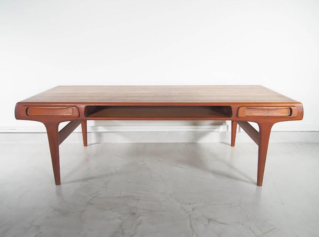 Beautiful large mid-20th century teak coffee or side table. Its design is attributed to a Danish furniture designer Johannes Andersen. The table has two convenient side drawers and an open shelf compartment in the middle. Drawers' bottom is