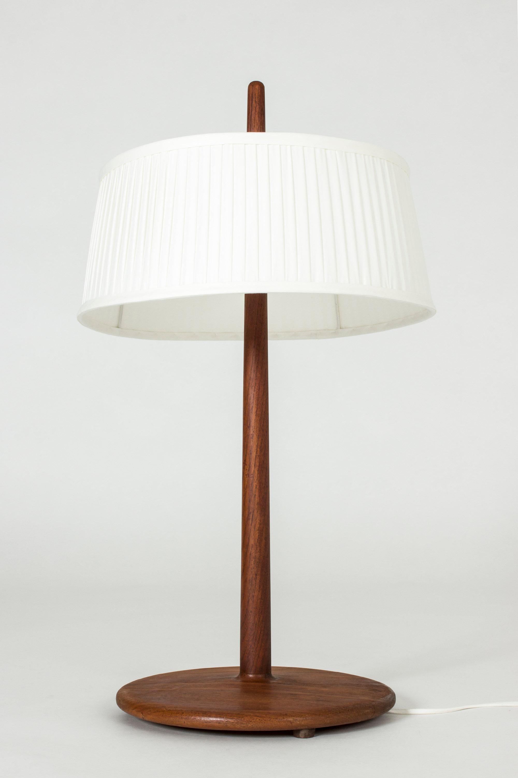 Cool table lamp by Alf Svensson, with a teak base and stem, where the tip of the stem shoots up out of the top of the open shade. Very nice, smooth teak in a streamlined shape.