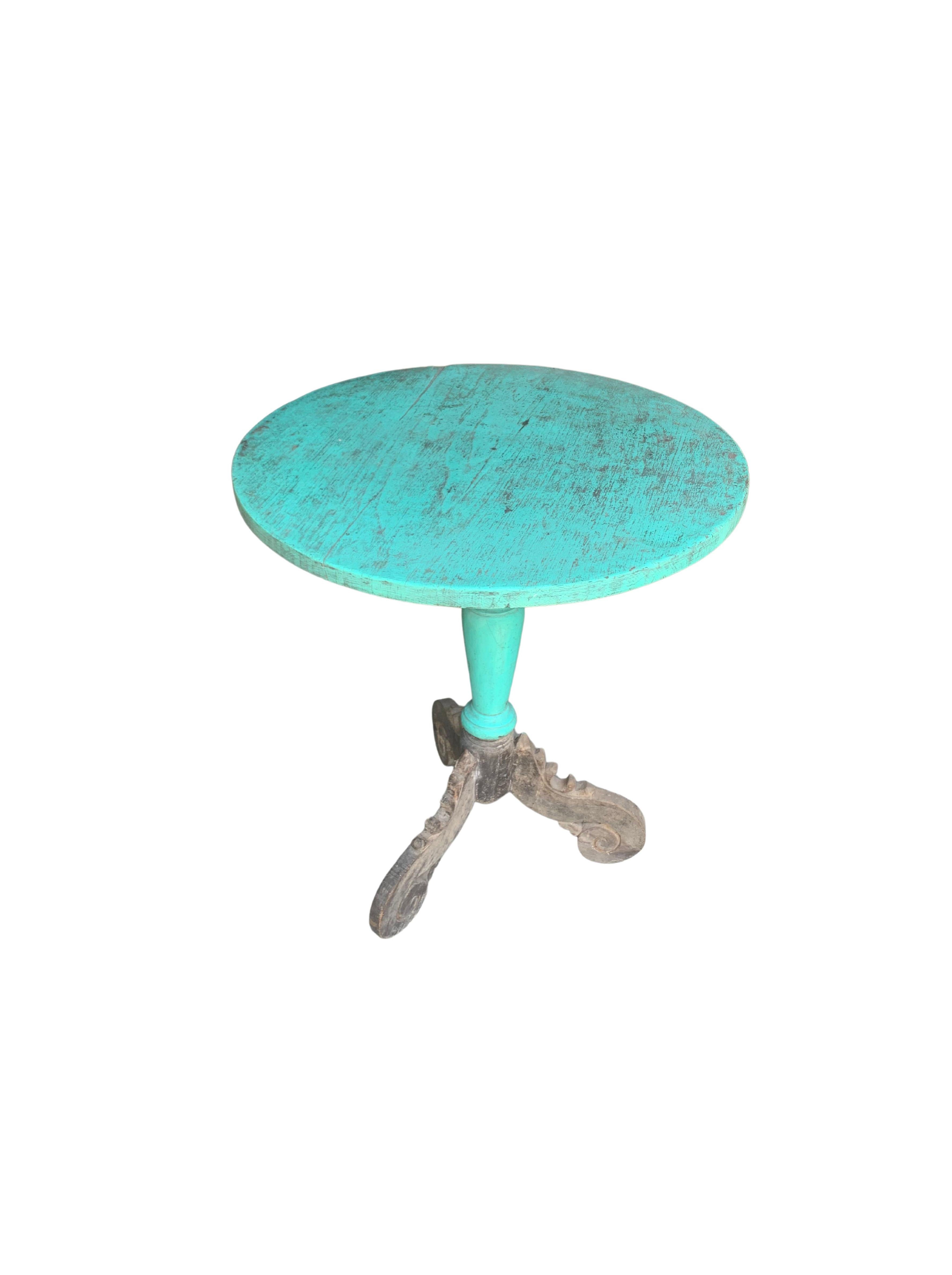 This teak round table was crafted on the island of Madura off the Northeastern coast of Java, Indonesia. It features hand-carved legs with floral detailing as well as a wonderful turquoise polychrome finish. A wonderful addition to any space. The