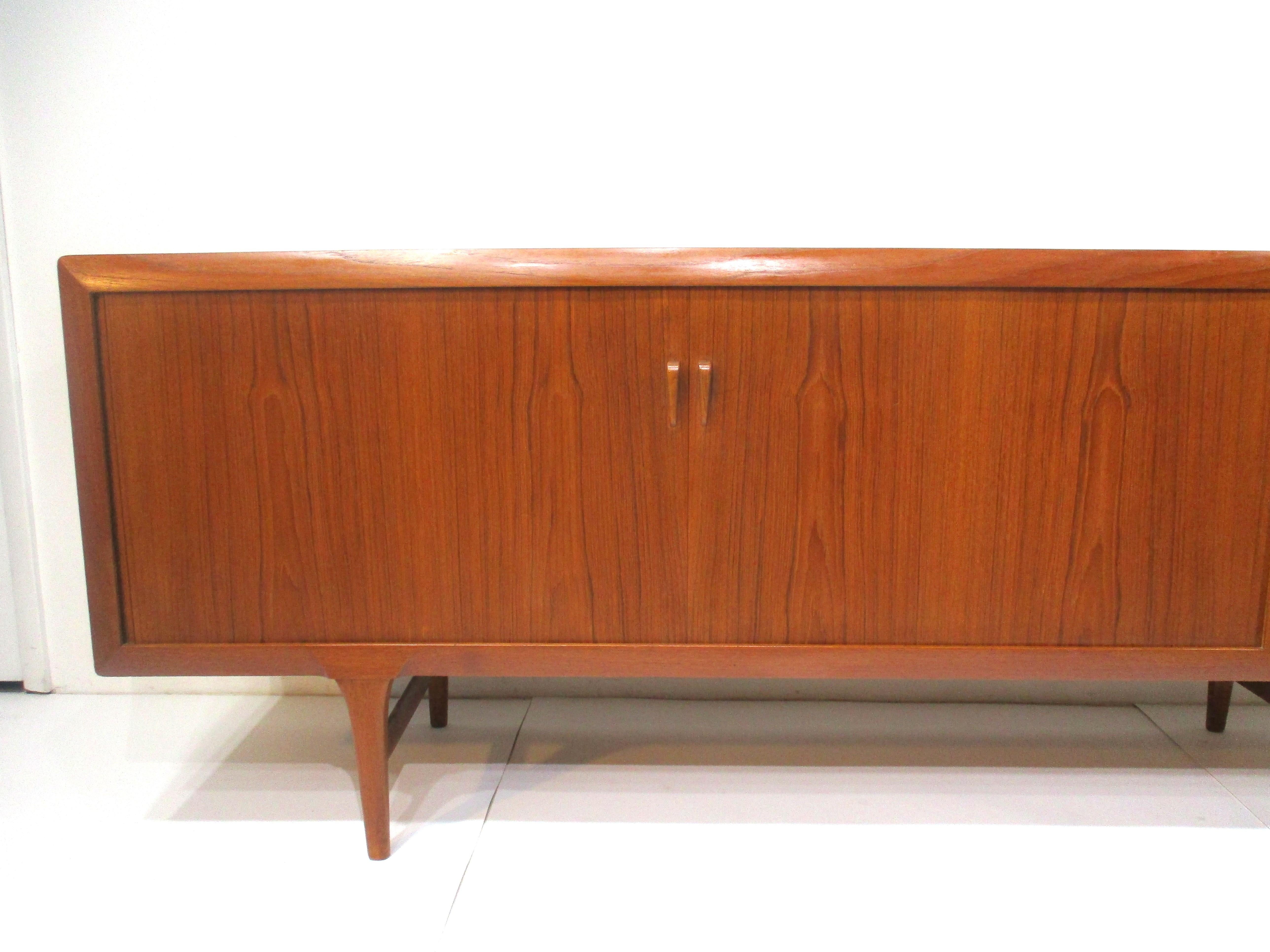 A very well crafted teak wood credenza / server fashioned by the early cabinetmakers in Denmark . Nice soft rolled edges , double tambor doors and sculptural pulls to the fronts of the drawers with the top one having a sliding tray all in keeping