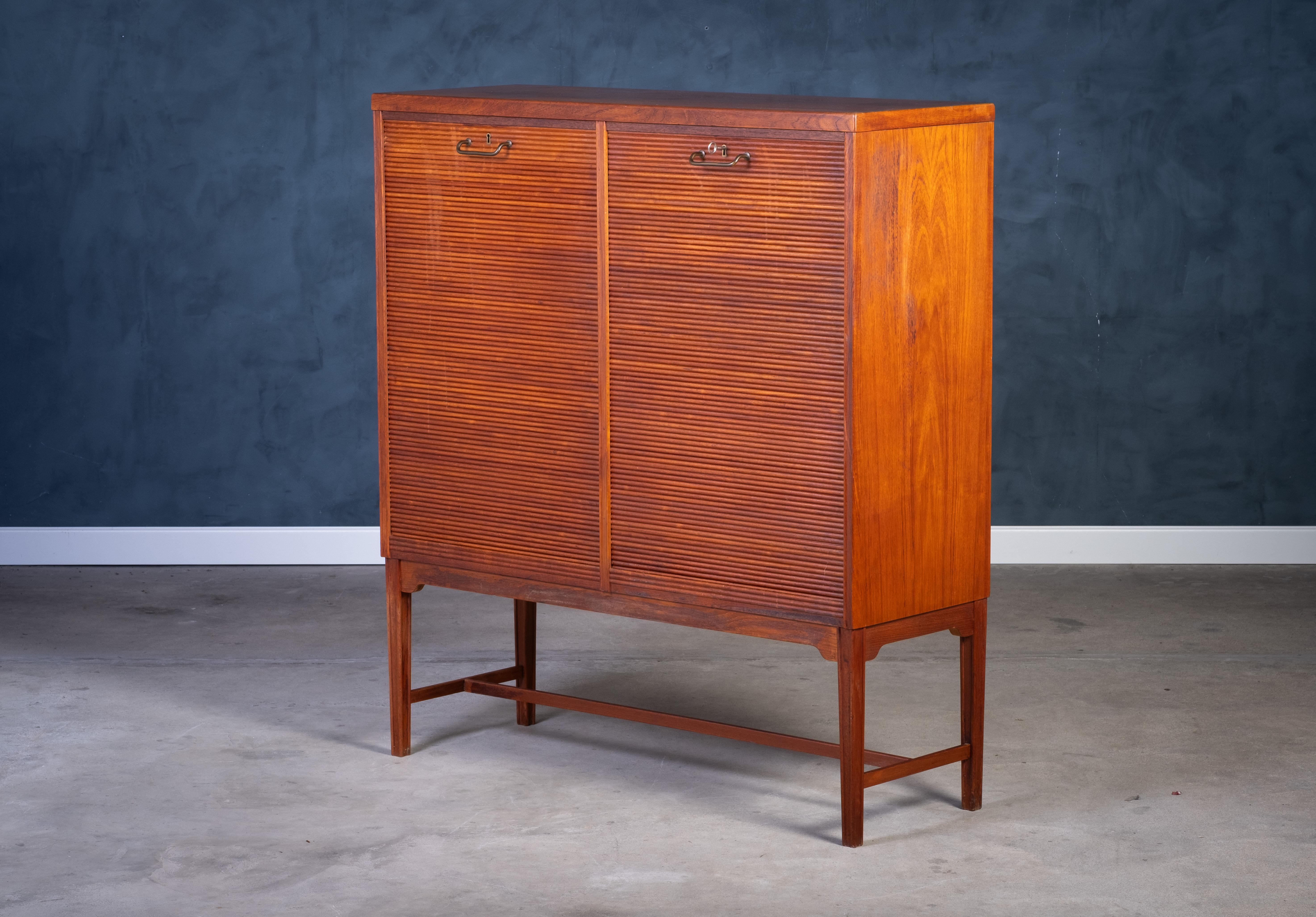 Archivschrank mit Tambourfront aus Teakholz aus den 1960er Jahren, mit Messinggriff und raffinierter dänischer Handwerkskunst. Die eine Seite ist mit ausziehbaren Schubladen ausgestattet, während die andere Seite geräumige Regale für eine