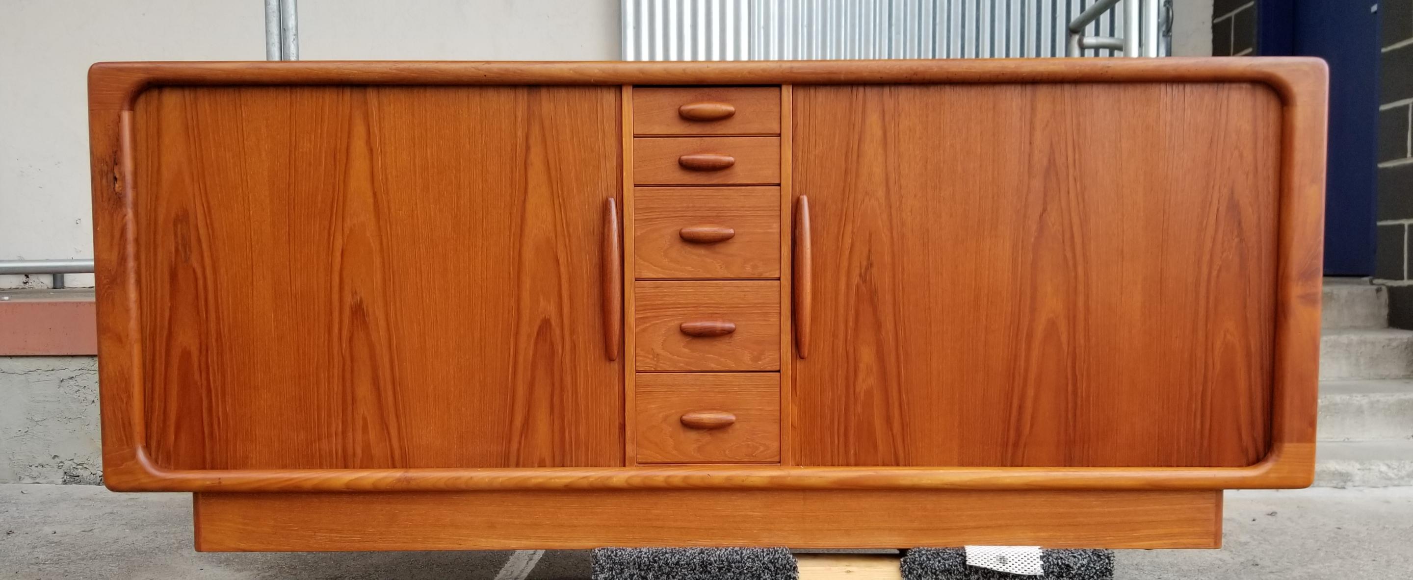 Teak Danish modern credenza by Dyrlund Furniture, Denmark. Sliding tambour doors open to a fitted interior with a bank of five solid oak finger jointed drawers and adjustable shelf. Five small drawers at center. Teak pulls. Measures 74.5