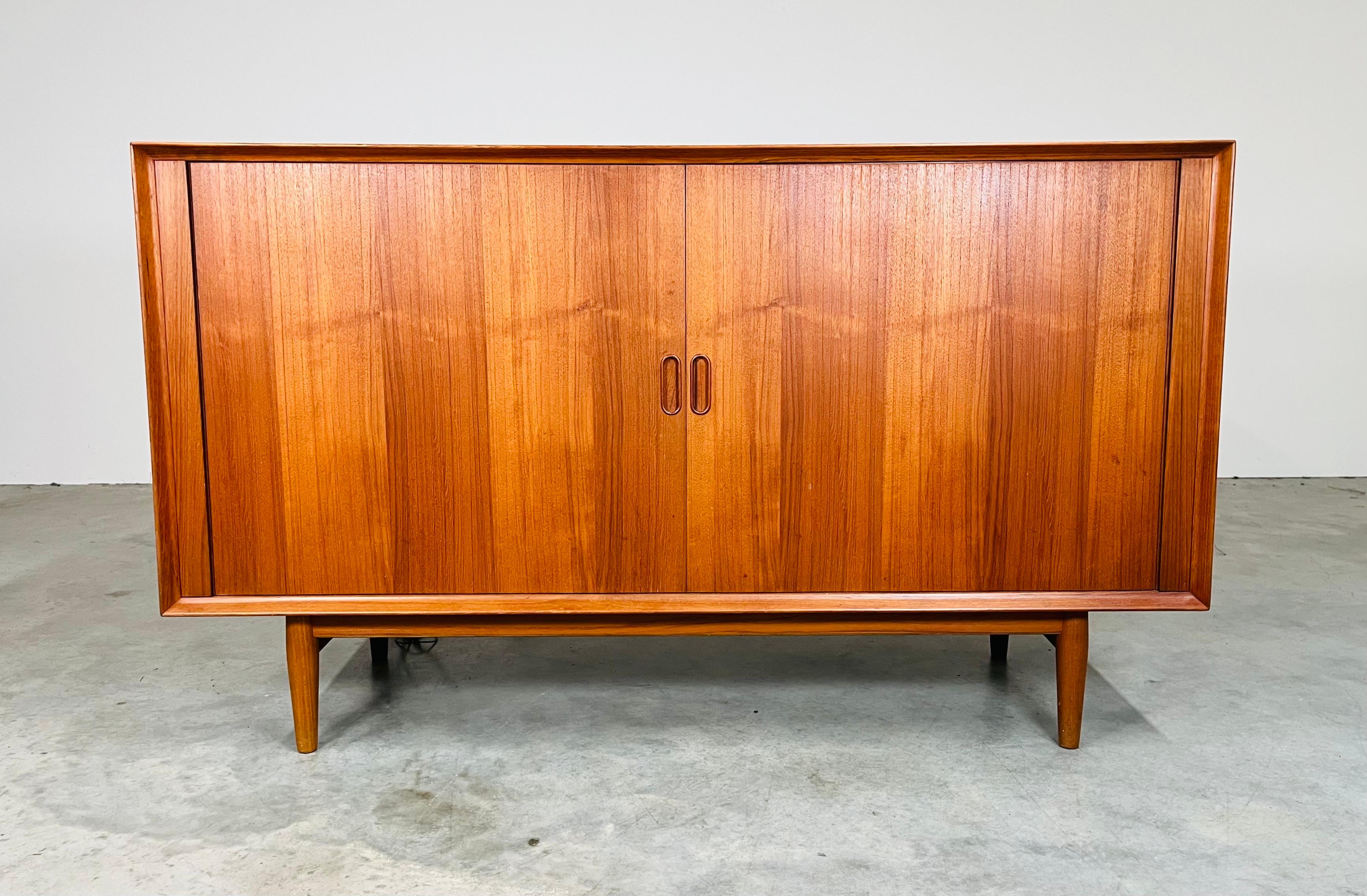 Mid-Century record console cabinet in teak designed by Arne Vodder for Sibast, Denmark. This unique media cabinet features sliding tambour doors and two flip top compartments with signature sculpted handles. Includes a middle storage section with LP