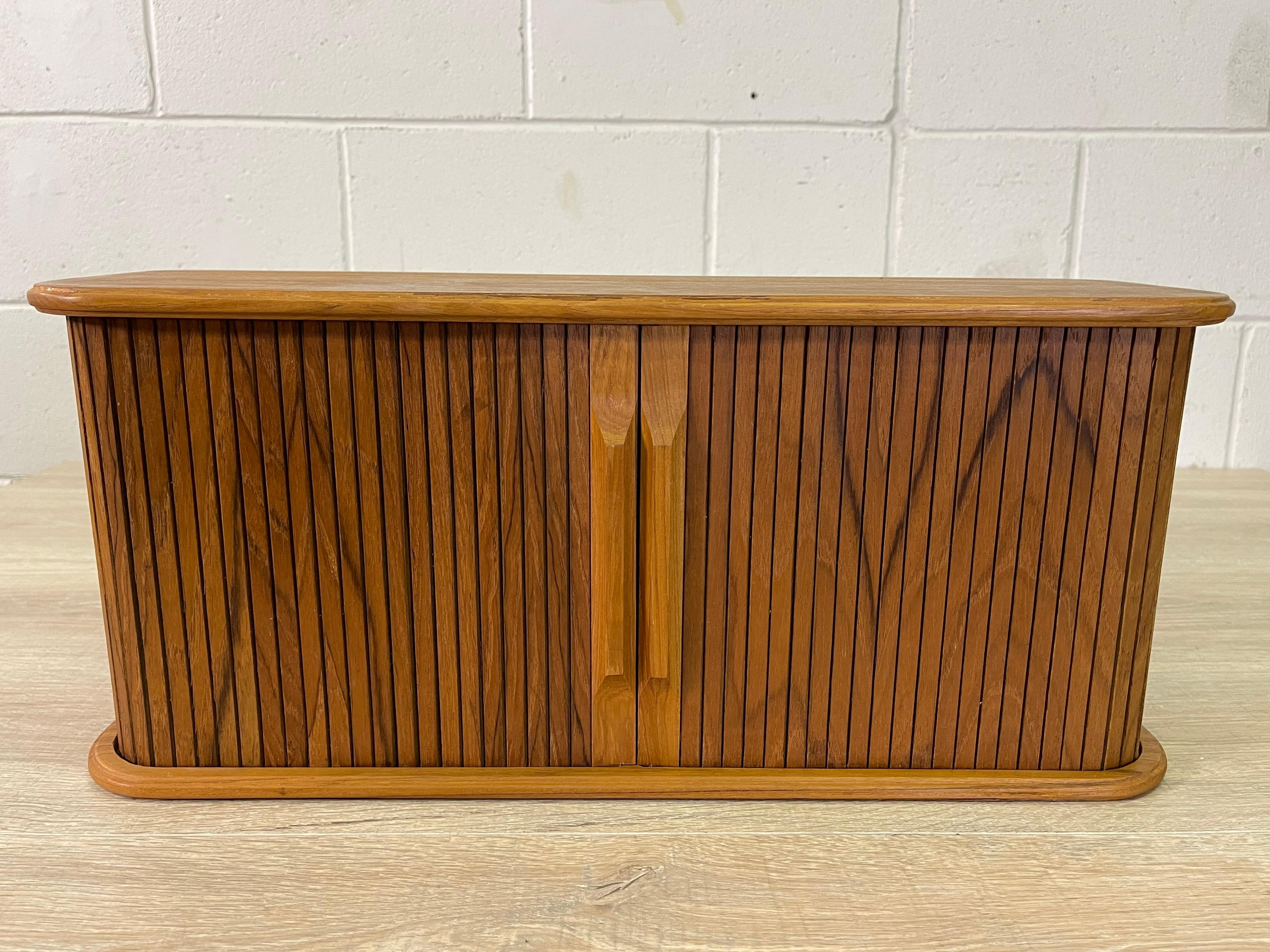 Vintage 1970s teak tambour door wall hanging shelf. Great two shelf design that hold lots of small objects. Hardware is included. Marked.