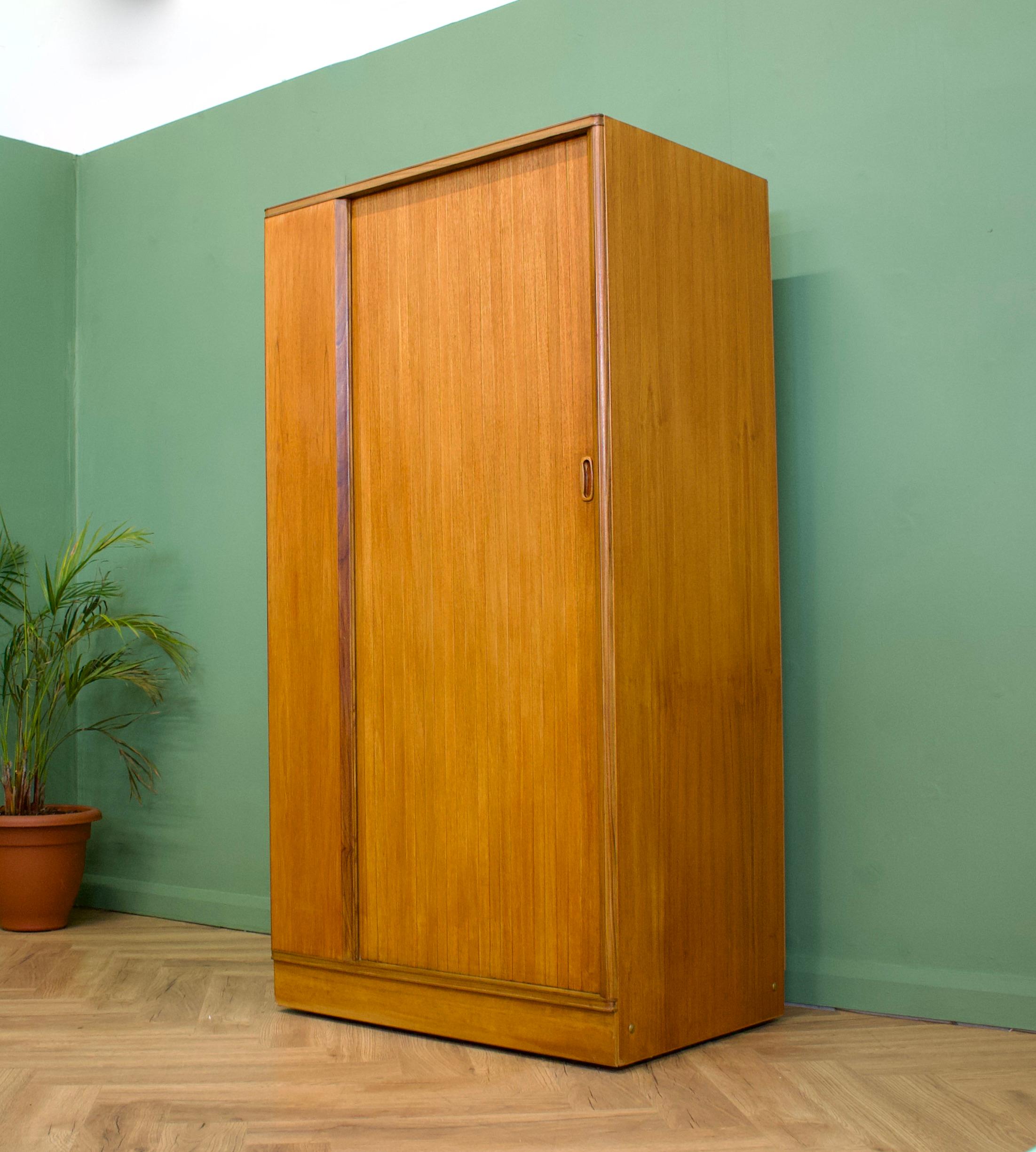 - Mid-Century Modern wardrobe.
- Manufactured by Austinsuite in the UK.
- Made from teak and teak veneer.
- Featuring a tambour door 
- The interior has a rail and shelves.