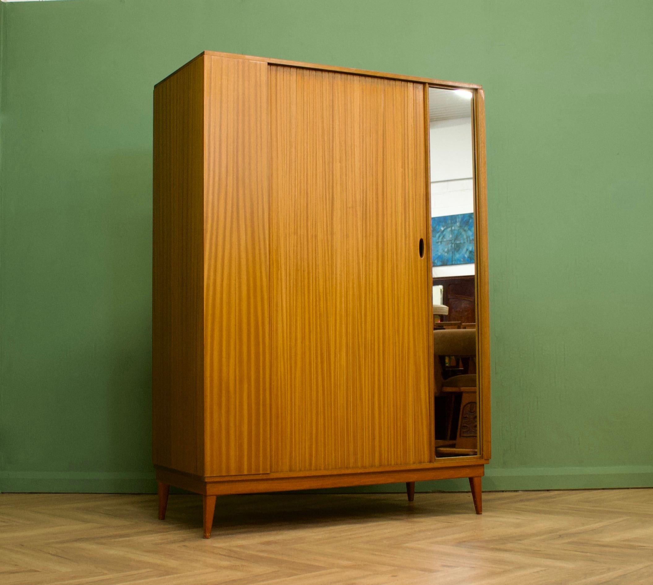 A freestanding teak wardrobe from Austinsuite - standing on stylish tapered splayed legs
These Austinsuite wardrobes have a unique design feature of a sliding tambour door - which runs very smooth
There's an external full length mirror - internally