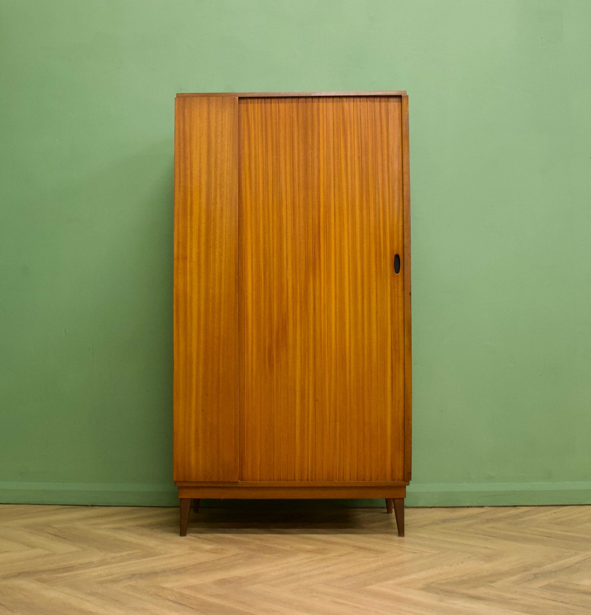 A freestanding teak wardrobe from Austinsuite - standing on tapered splayed legs
Featuring a tambour door, a hanging rail and shelves
 