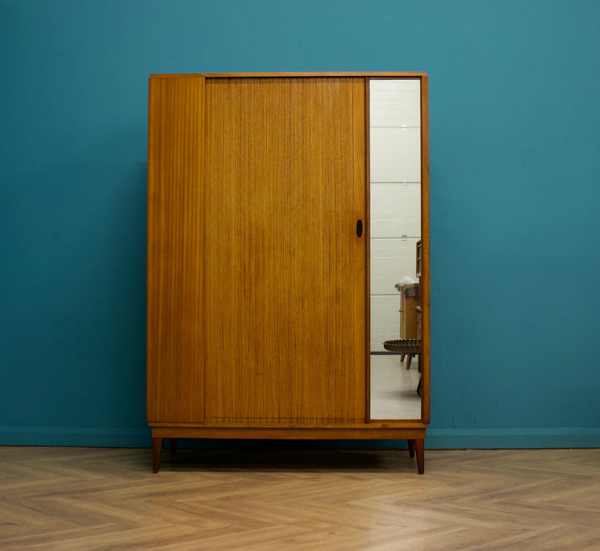 A freestanding teak wardrobe from Austinsuite - standing on stylish tapered splayed legs
These Austinsuite wardrobes have a unique design feature of a sliding tambour door - which runs very smooth
There's an external full length mirror - internally