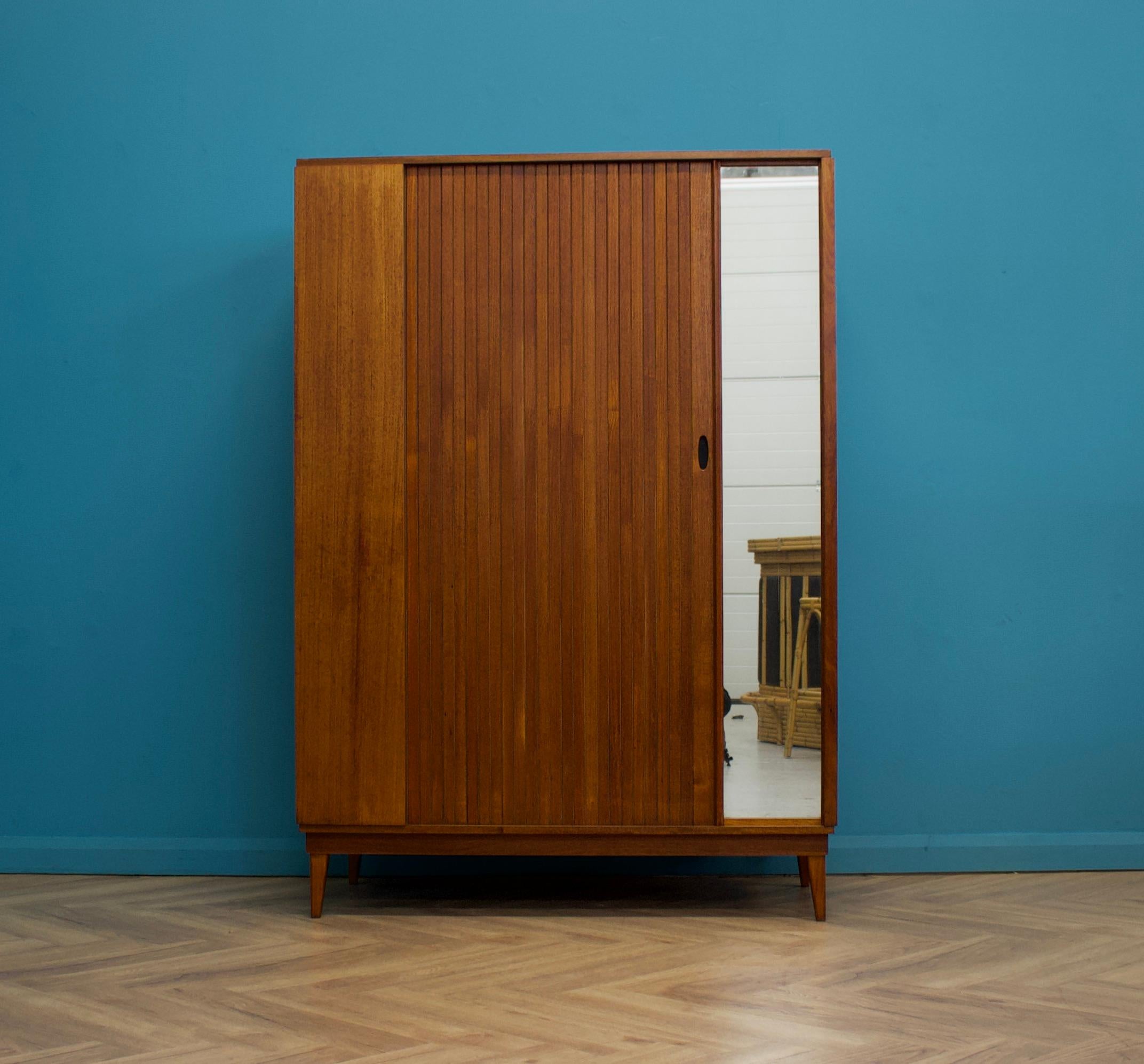 A freestanding teak wardrobe from Austinsuite - standing on stylish tapered splayed legs
These Austinsuite wardrobes have a unique design feature of a sliding tambour door - which runs very smooth
There's an external full length mirror - internally