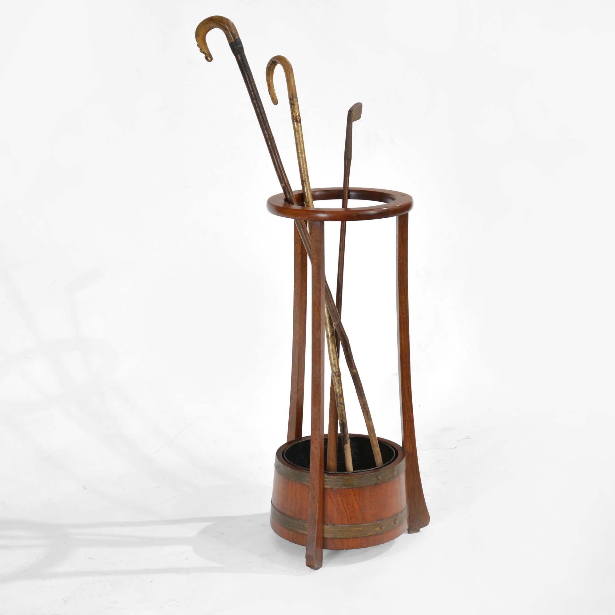 Teak Umbrella or Walking Stick Stand by R.A. Lister
Brass bound barrel base with a trio of supports to a circular top, stands on shaped feet.  With original removable black japanned tin liner (to catch water from the umbrella).  R.A. Lister & Co
