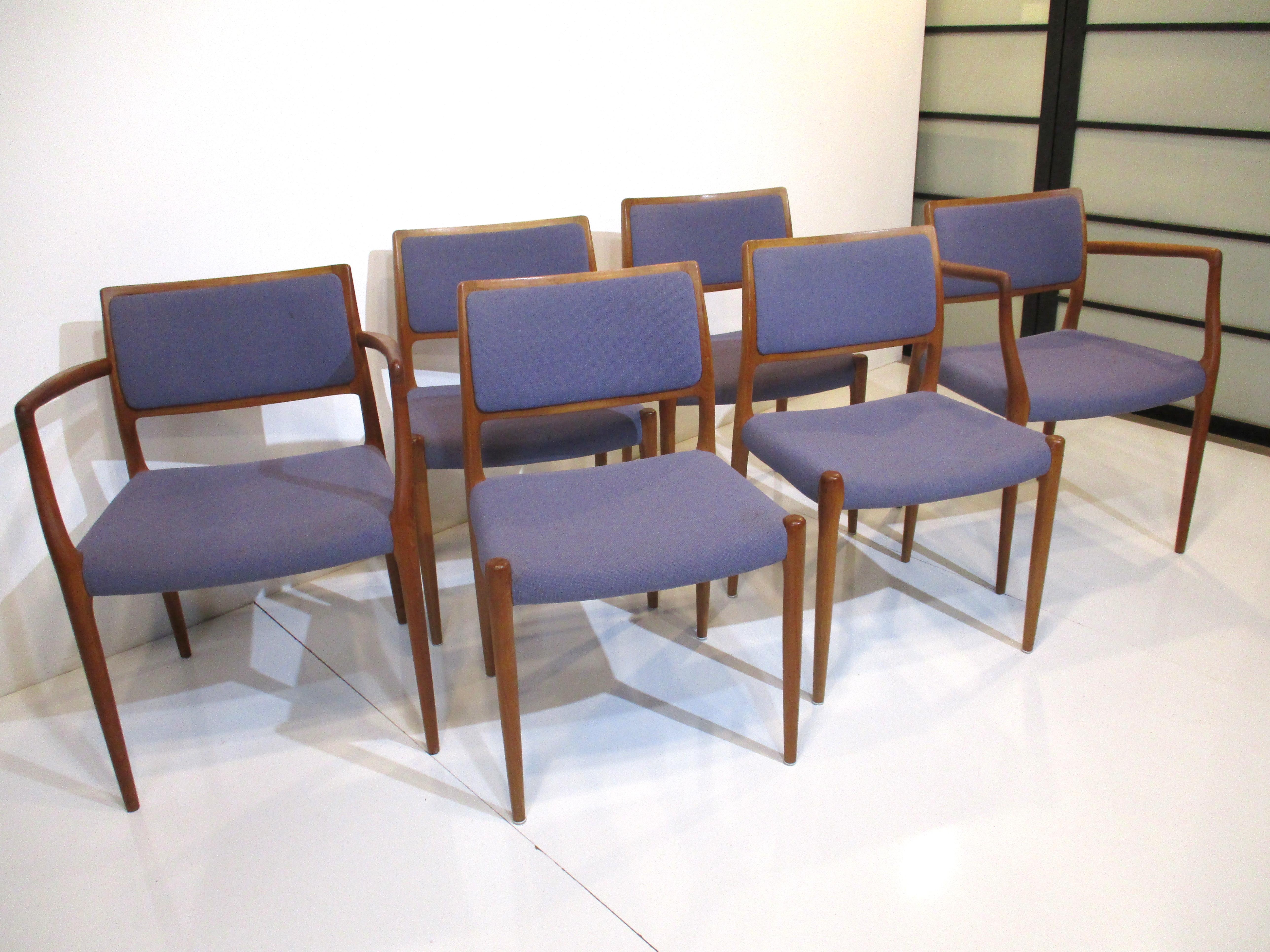 A set of six sculptural teak wood framed dining chairs upholstered in a tight woven light purple violet fabric. The set has four side chairs and two arm chairs which are very well crafted and comfortable designed and manufactured by Niels Otto