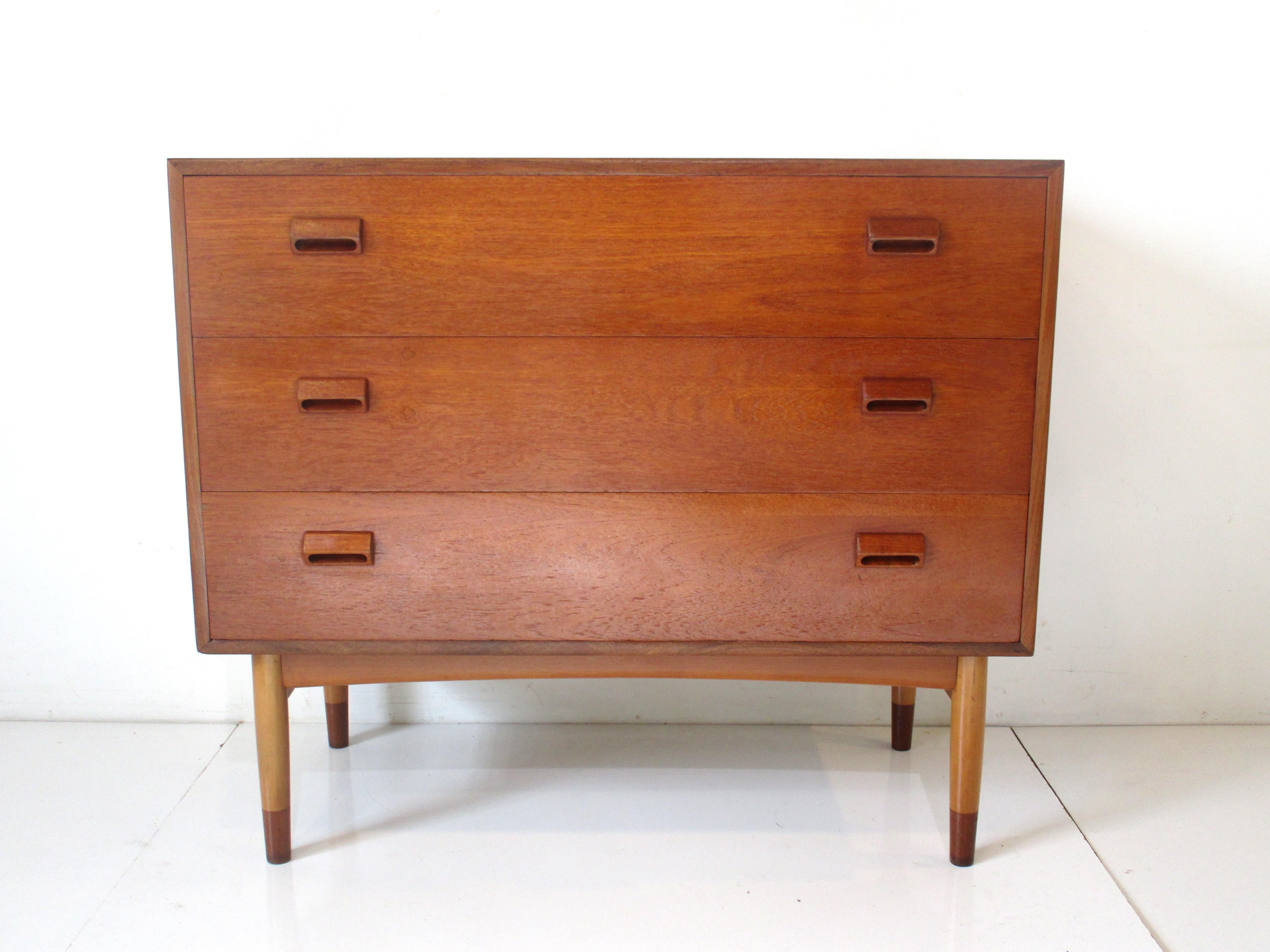 A very well designed teak wood vanity dresser with a top drawer that has a pull out and flip up mirror. The front of the piece folds down revealing storage slots to the left and three drawers to the other side. The two bottom drawers have typical
