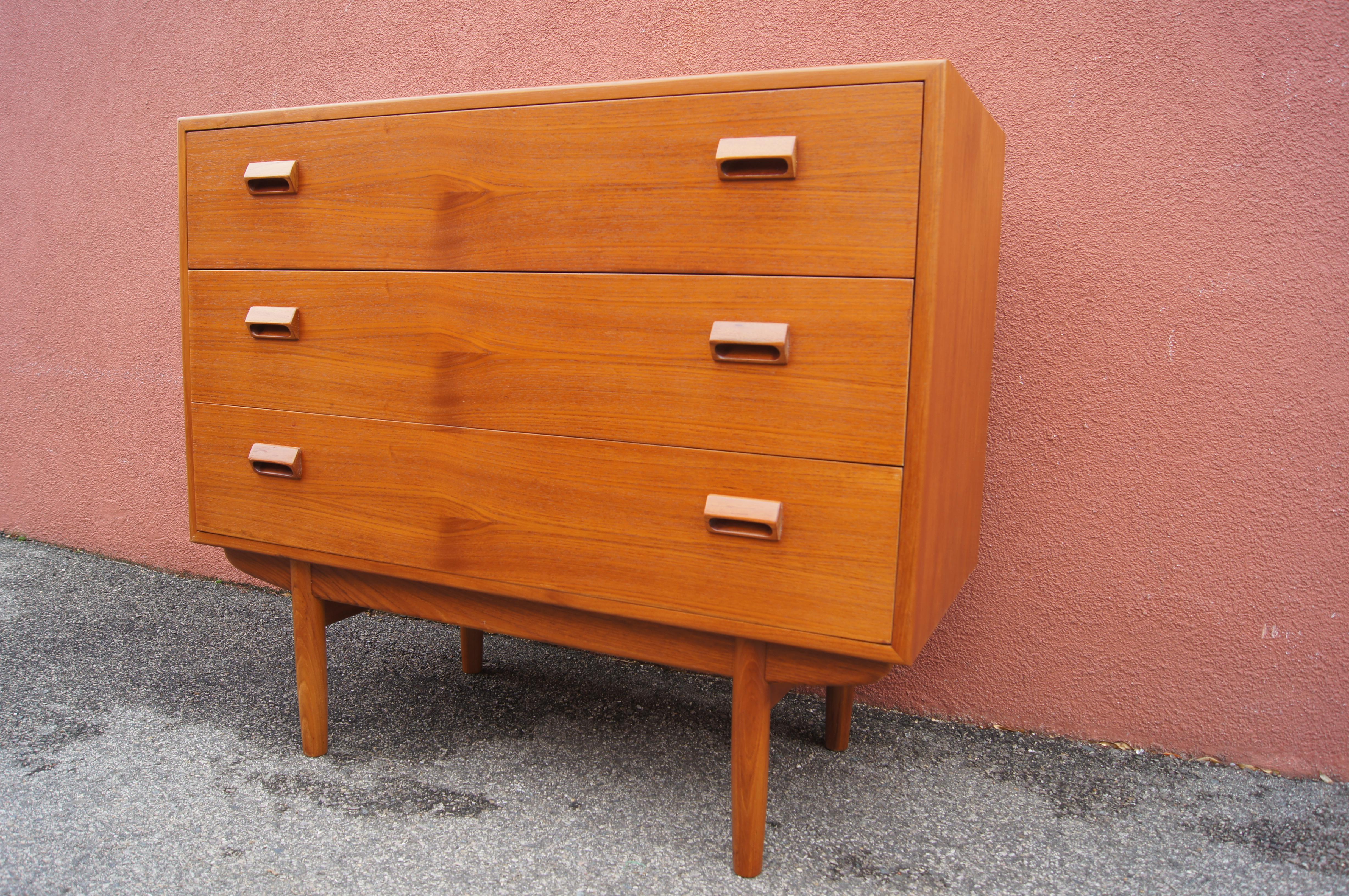 This midcentury teak dresser, designed by Børge Mogensen, sits on a plinth base. The case has two capacious drawers. A third, topmost drawer front drops down to become a desktop and reveal tiered cubby shelves and three small drawers. Additionally,