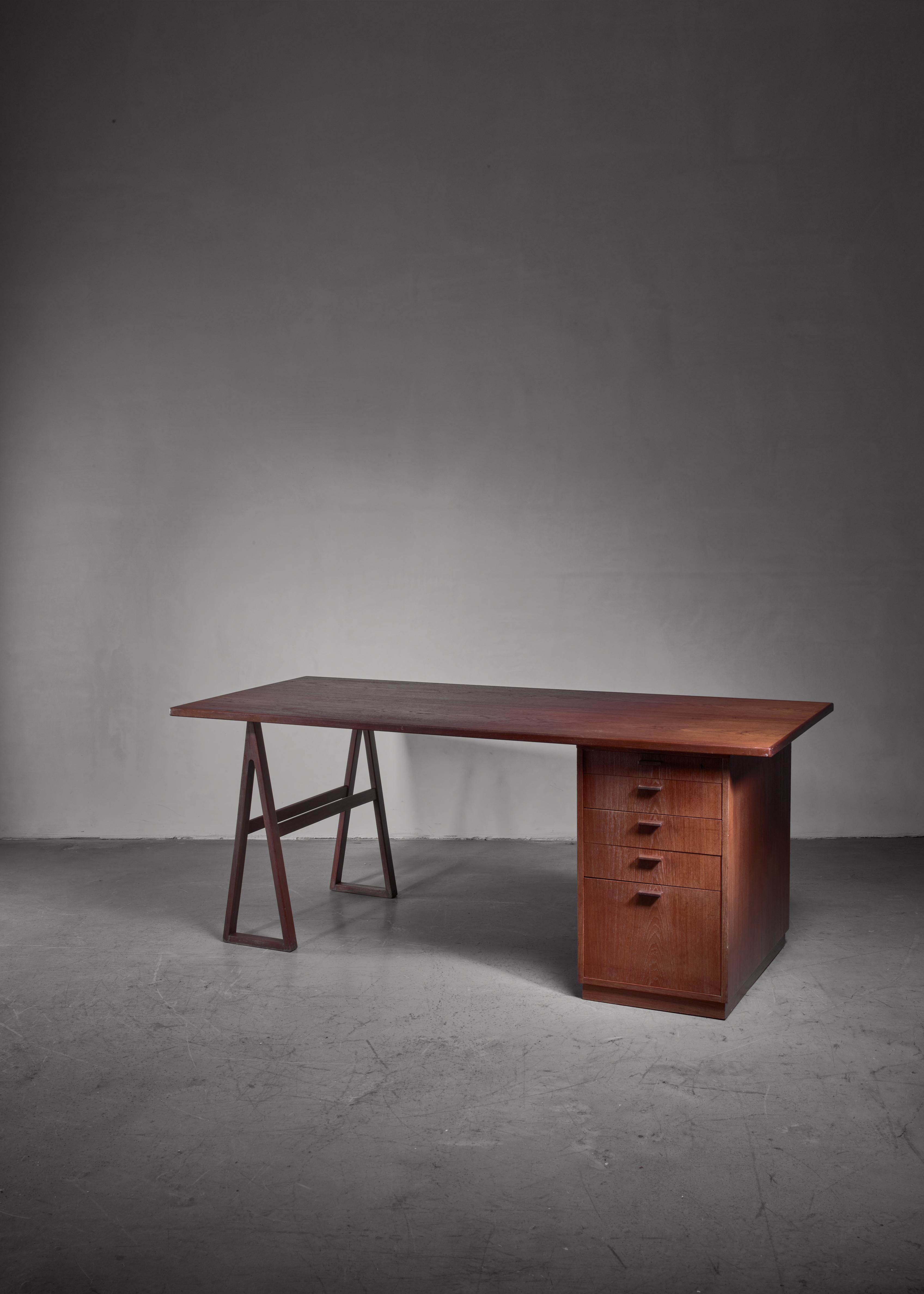 A Scandinavian Modern teak veneered desk from Sweden. The top rests on a tressle and a storage unit with five drawers. The construction allows to place the chest or drawers at either side.