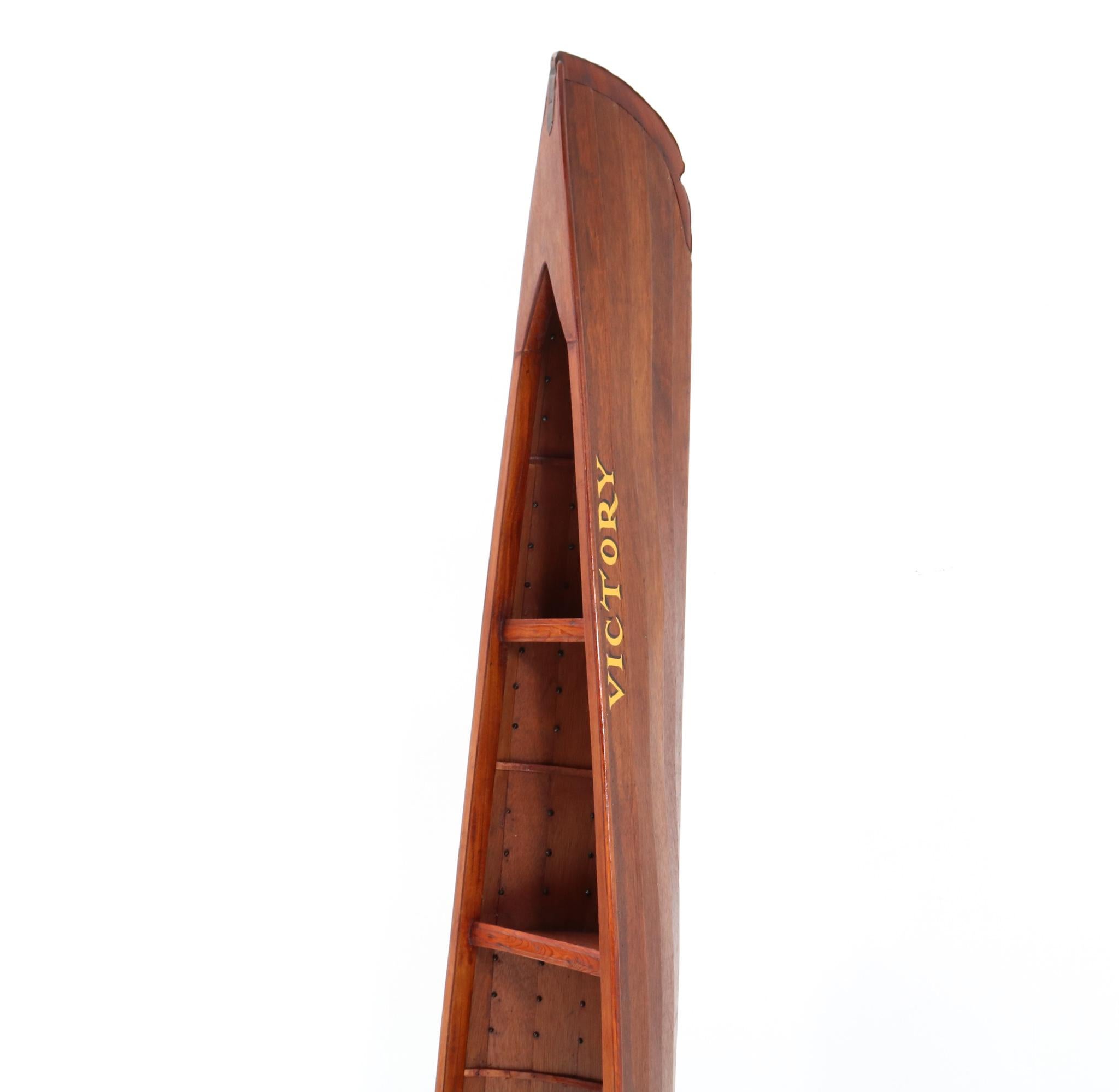 Stunning Vintage half boat bookcase.
Striking English design from the late 20th Century.
Resembling half a canoe boat, this unusual solid teak bookshelf is
characterised by its ascending bow and hull shelves which echo the
position of the boat's