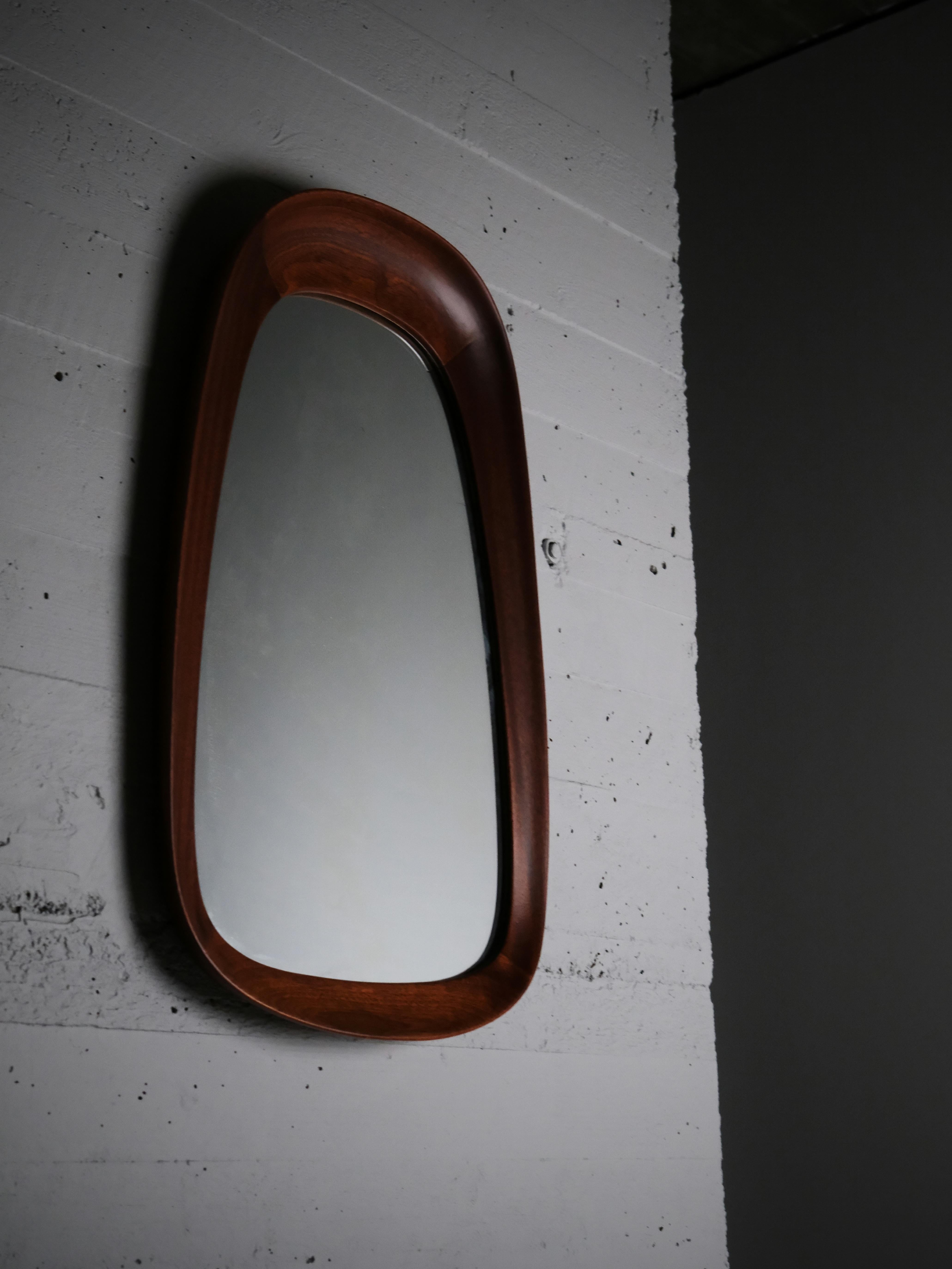 Wall mirror designed by Åke Fribyter for Glas & Trä, Hovmantorp in Sweden during the 1950s. 

Sculptural design in teak. Mirror glass with stains. 