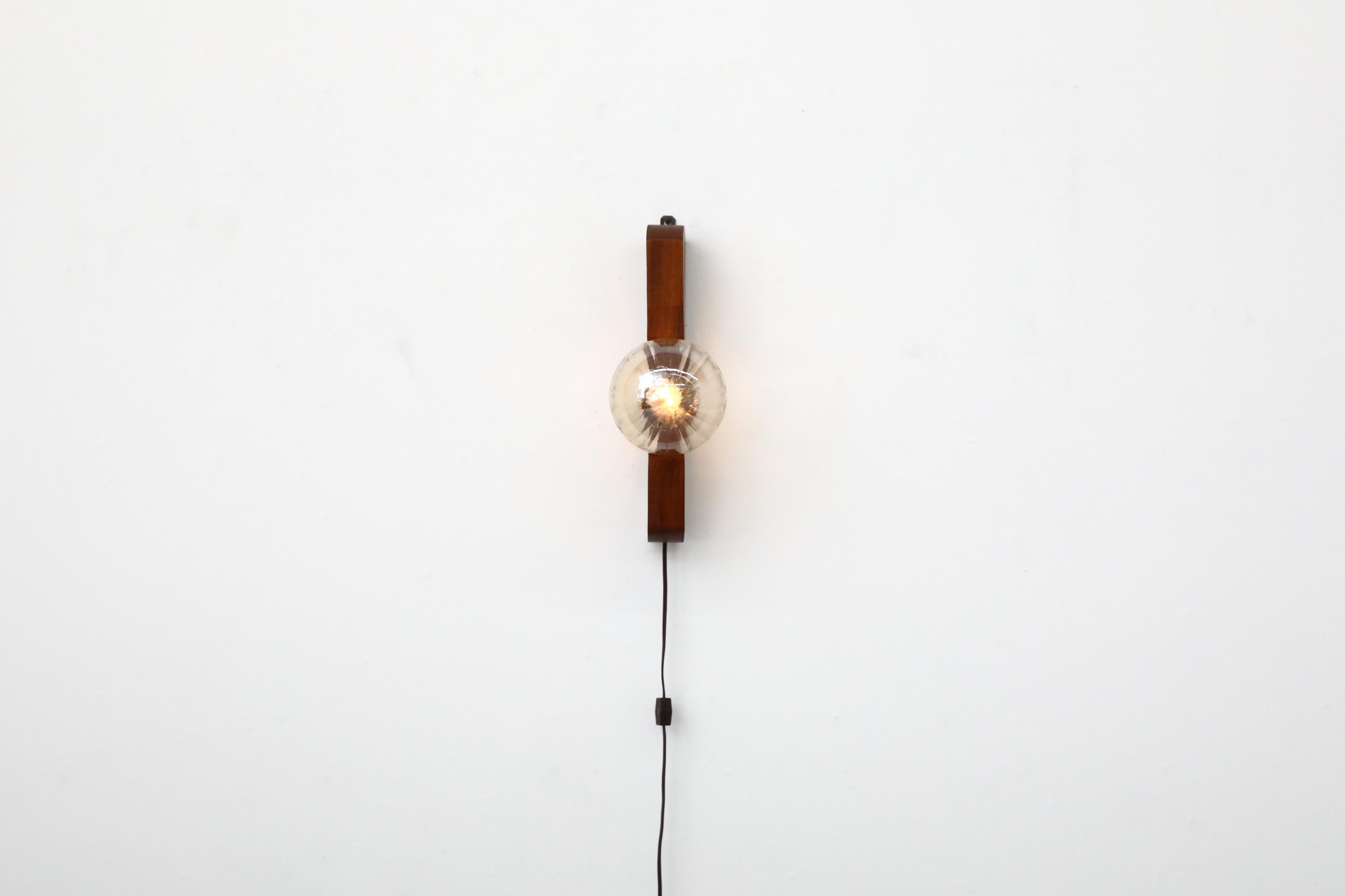 Lovely German Brutalist solid wooden base light with a cut out that houses an amber globe by Temde Leuchten, 1970's. The light can be hung vertically from a hook that allows the lamp to be easily moved. In original condition with some age