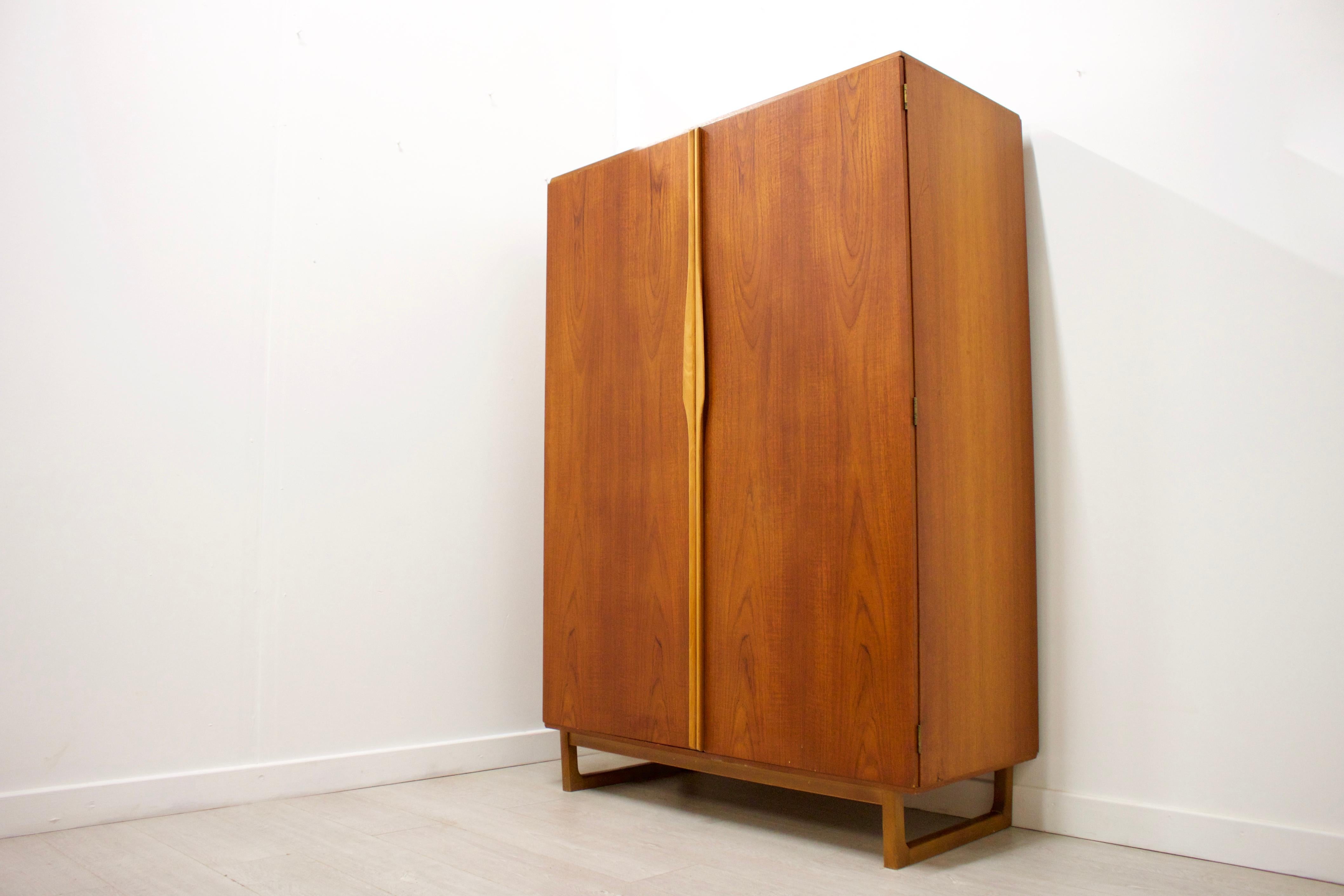 - Mid-Century Modern wardrobe
- Manufactured by Stonehill
- Made from teak and teak veneer
- Featuring a hanging rail, a shoe rack, and a mirror on the inside to the middle.