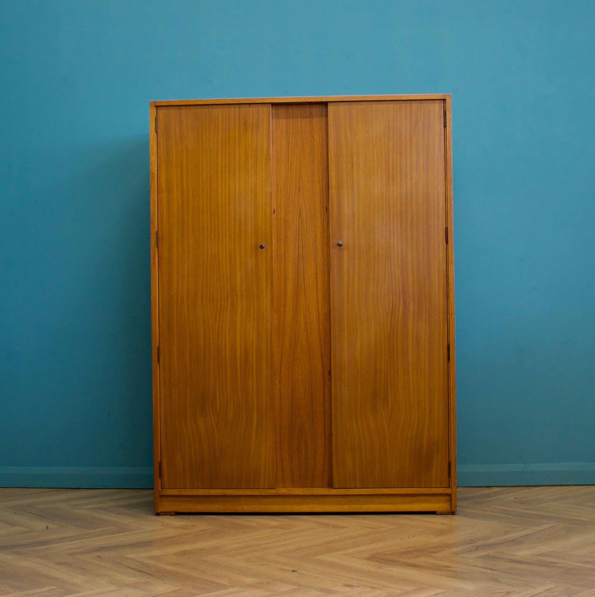 A freestanding double door teak wardrobe from Uniflex - designed by Gunther Hoffstead
Made during the 1950s
 
Fitted out with two clothes rails and a shelf 
The style of this wardrobe is quite minimalist - with it's clean lines 
 
This wardrobe can