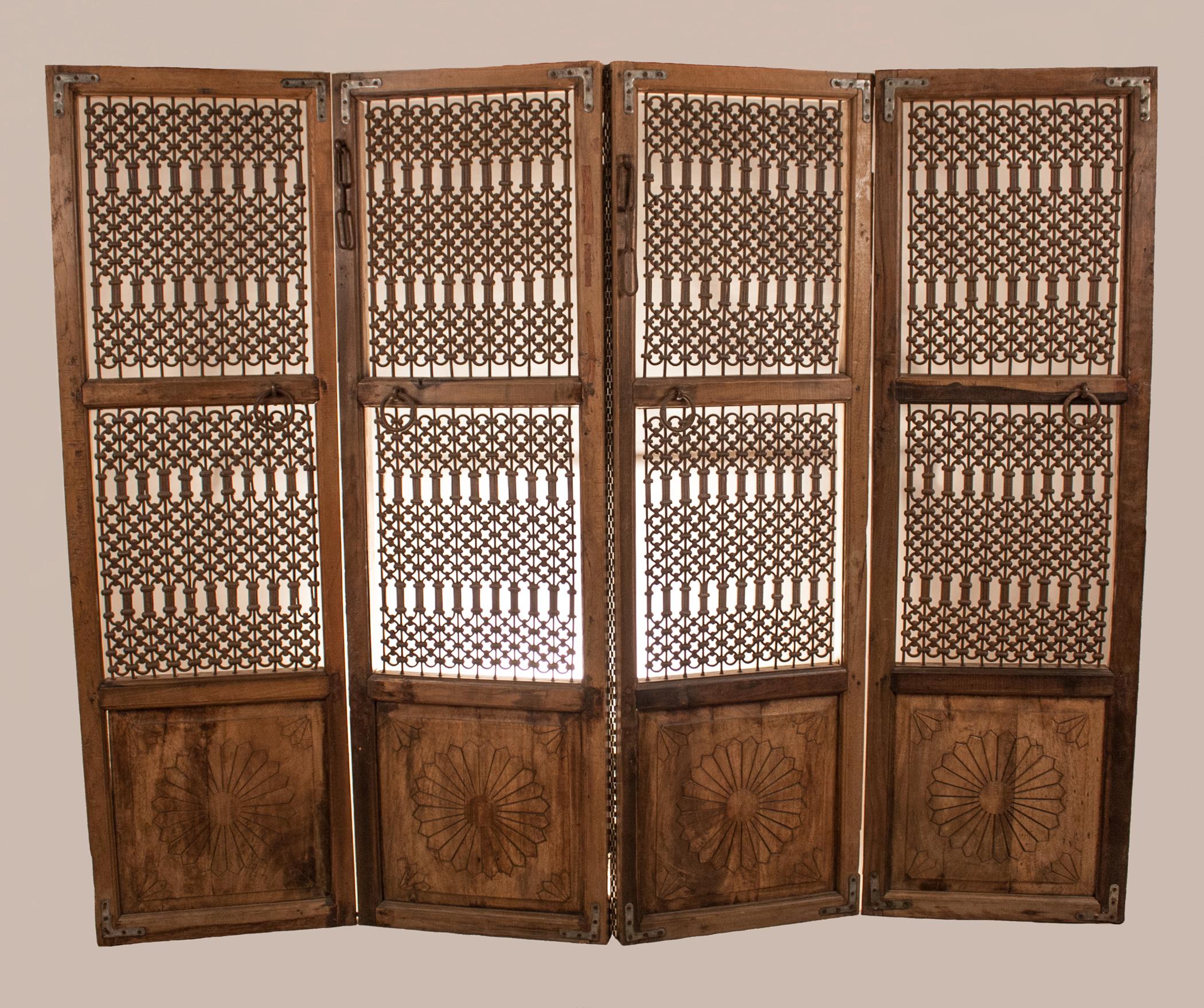 Midcentury solid teak wood and iron four-panel decorative screen from Gujarat. These architectural panels are in very good condition, with appealing patination of the wood. The bottom of the panels is hand carved with a simple lotus flower motif.