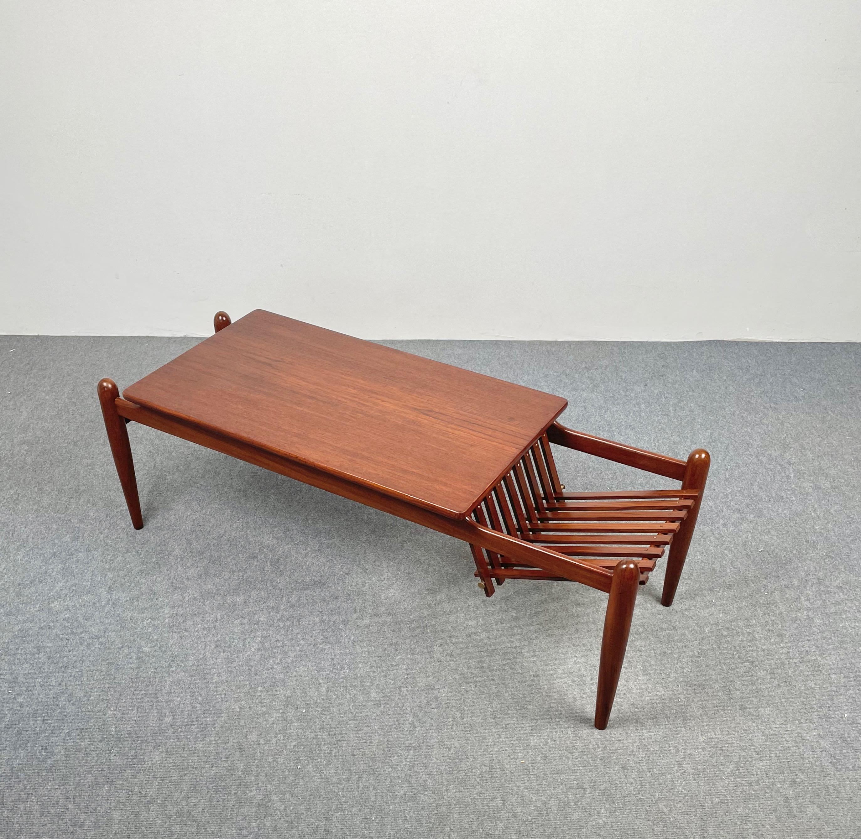 Coffee table and magazine rack in teak made in Italy in the 1970s. 
The magazine rack part features interlocking wooden slats connected by a brass pin.