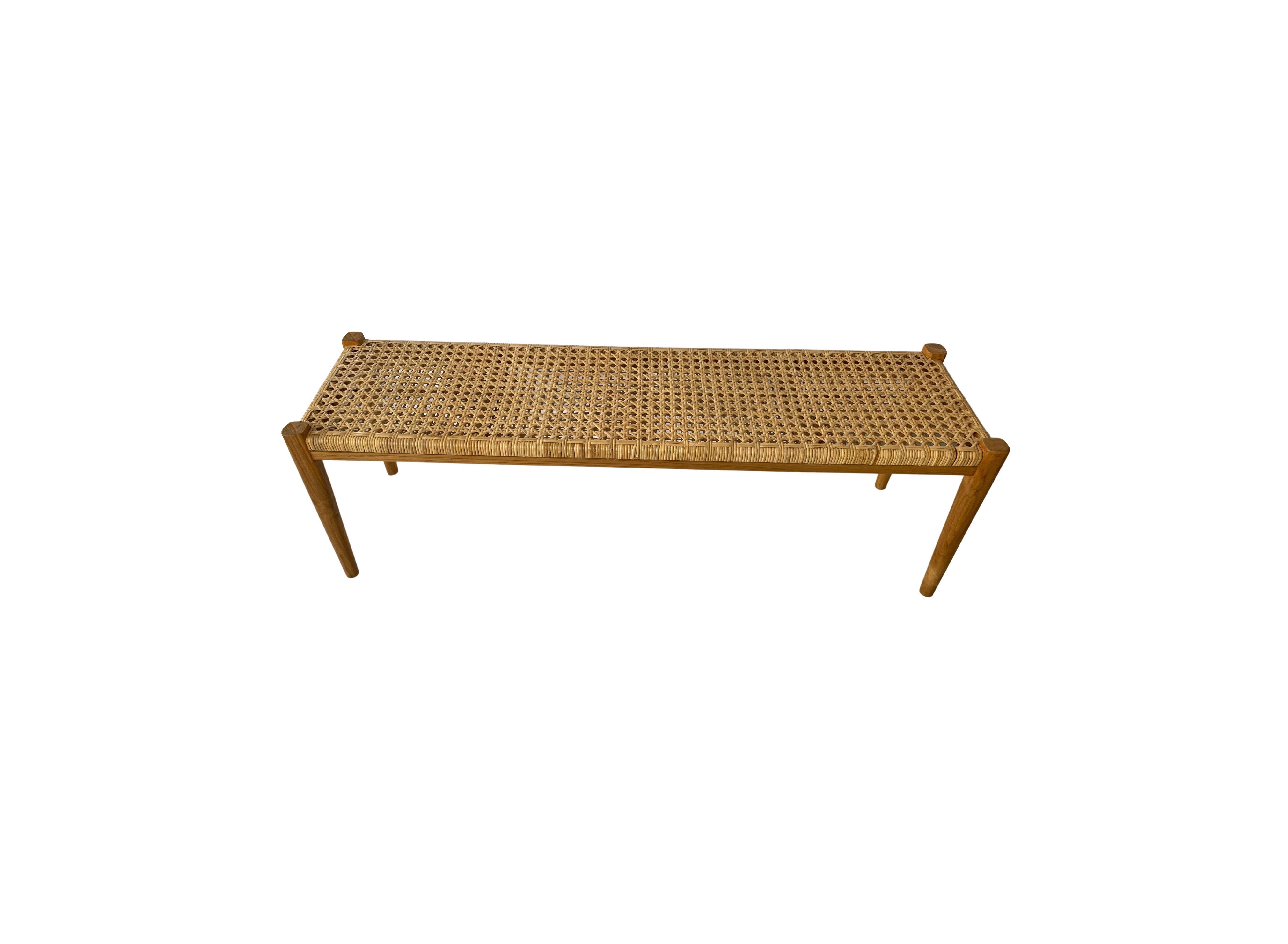 Un banc à sangles en rotin tressé et encadré de teck, fabriqué à la main. Ces bancs sont fabriqués par des artisans locaux selon une technique d'assemblage du bois sans clou. Ils présentent une texture bois subtile et sont robustes et résistants.