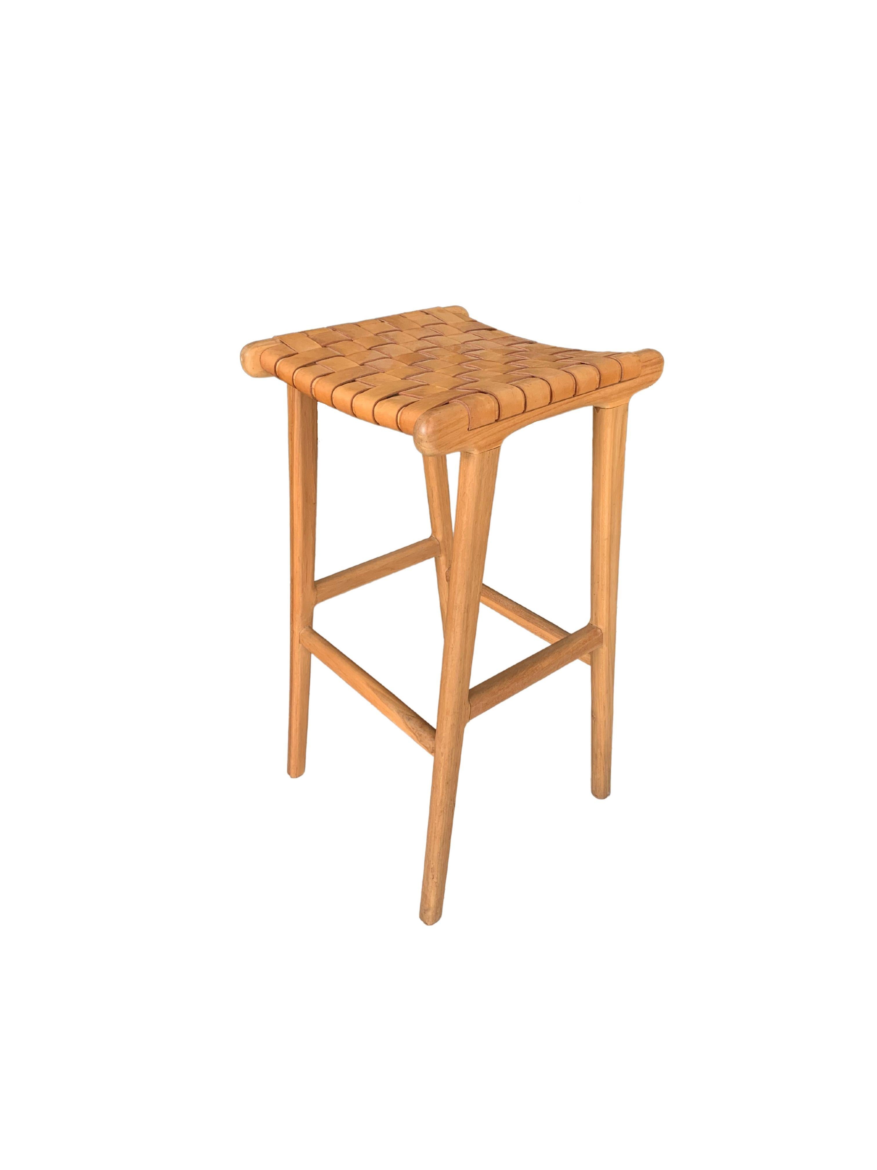 A hand-crafted teak framed & woven leather strap stool. These stools are crafted by local artisans using a wood joinery technique without the use of nails. They feature a subtle wood texture and are robust and sturdy.