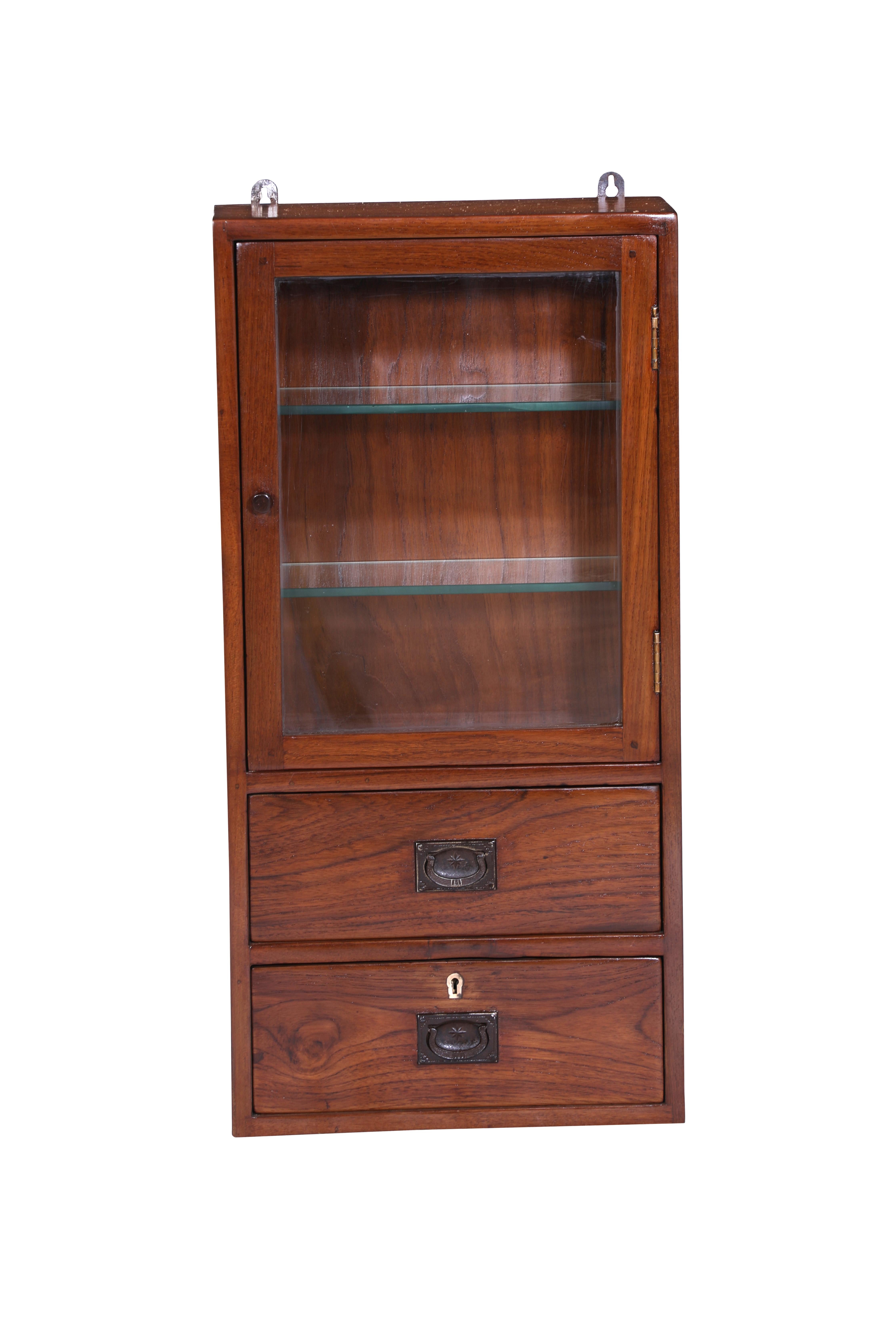 Teak wood wall cabinet with glass front and two interior glass shelves.  Two lower cabinet drawers with iron flush-mount drawer pulls.  Two hooks at the top to allow for hanging.  Refinished.  Colonial British.

The Lockhart Collection is a