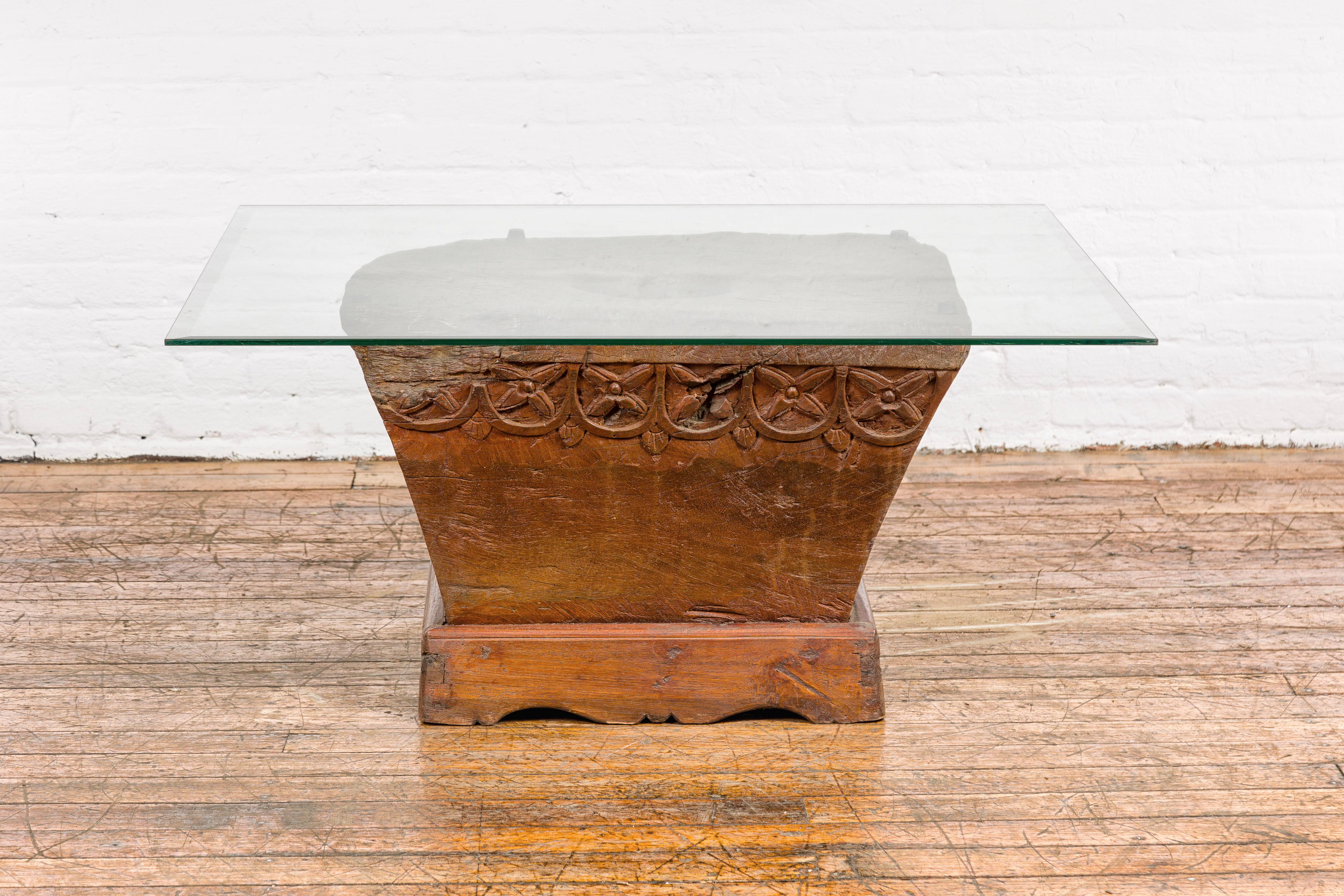 A Primitive teak wood mortar converted into a coffee table base, with floral carved accents, bracketed base and rustic character. Step into a world of rustic charm and unique design with this Primitive teak wood mortar, ingeniously repurposed into a
