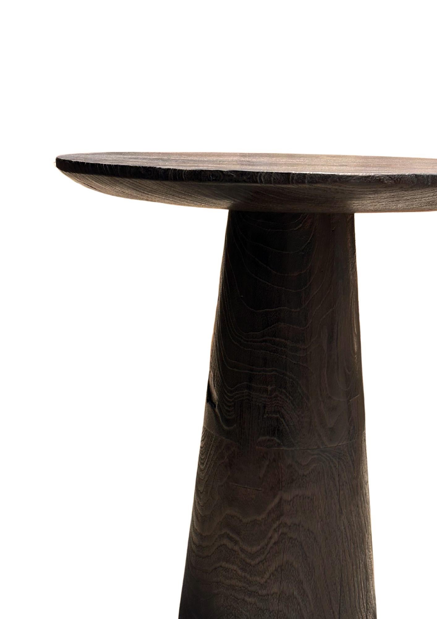 This exquisite teak wood side table is a stunning showcase of nature's beauty, with rich, intricate wood textures and warm, varying shades that make each piece truly unique. The table’s surface features a captivating grain pattern, where swirls and