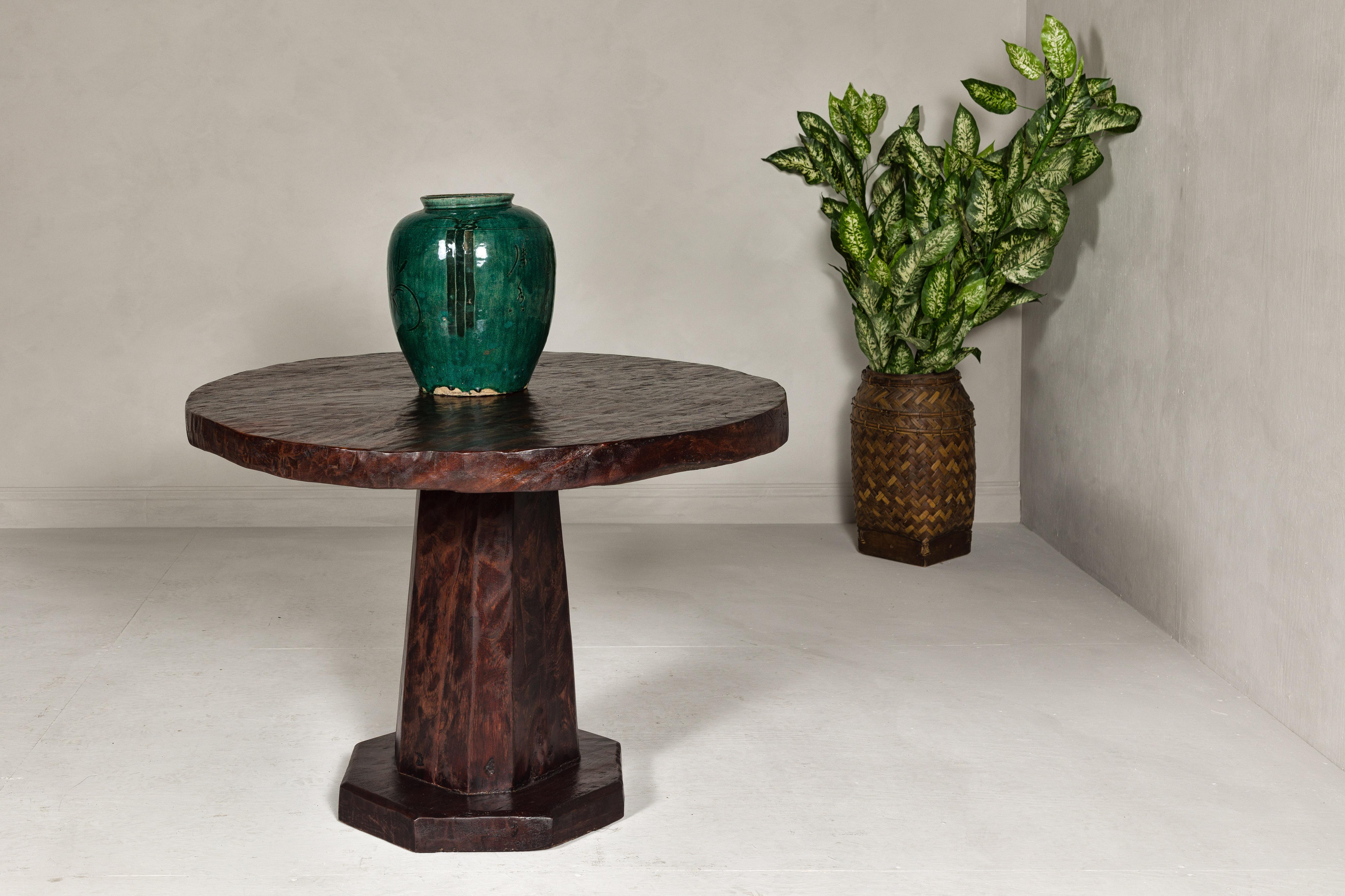 A teak wood center table with circular top, pedestal base and dark stain. This vintage teak wood center table, with its circular top and pedestal base, is a testament to classic design and skilled craftsmanship. The table has been professionally