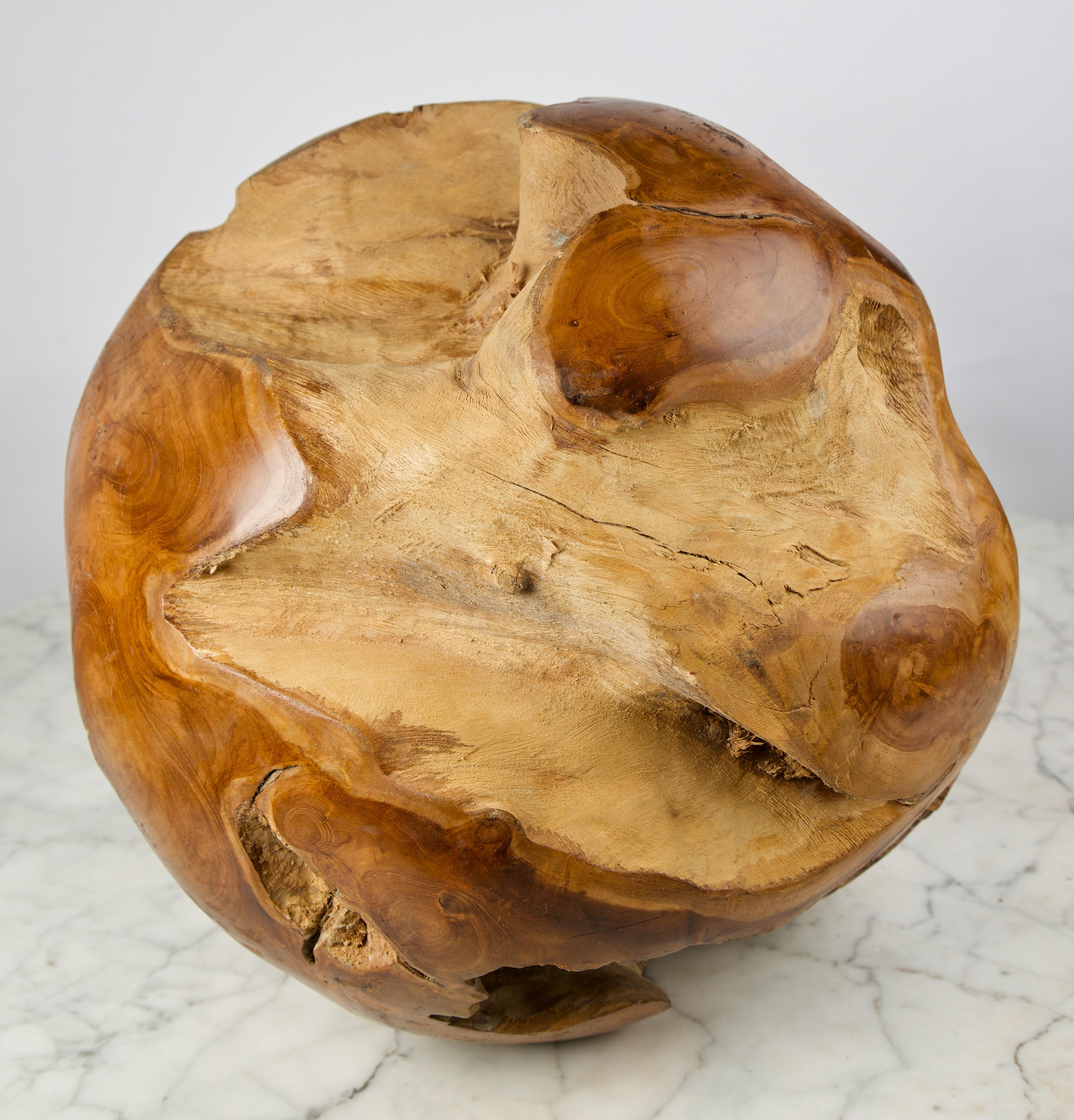 This sculpture is a hand carved reclaimed natural teak wood root sphere. The outer section is polished and the inner root left untouched in contrast. By leaving the live edge it gives the inner surface of the ball a unique organic shape and