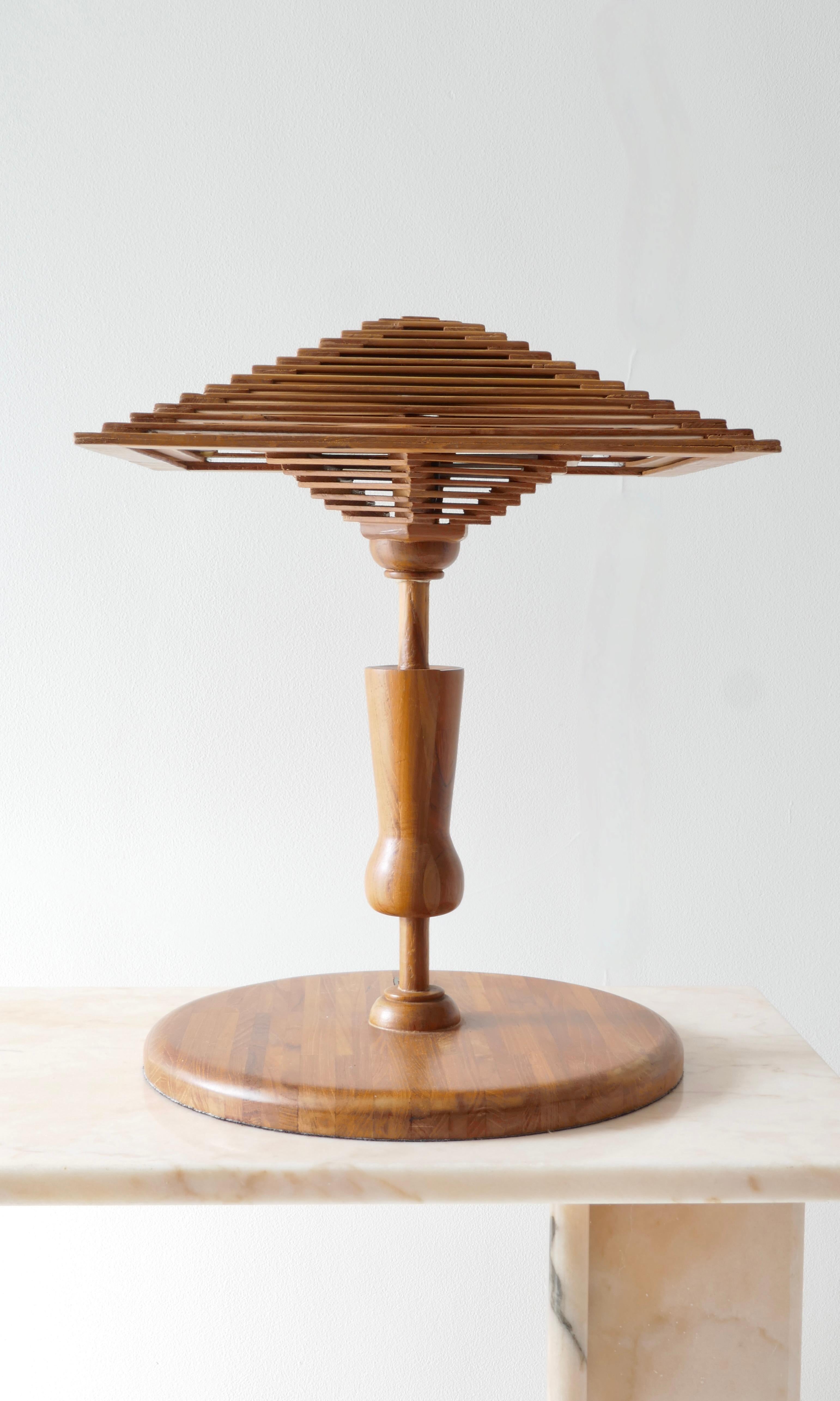 A unique and original table lamp in teak wood crafted like a Japanese house. Probably an architect design lamp for its originality hints to it.
A round base and a shade in the shape of Japanese house roof which diffuses a soft light.
The lamp has