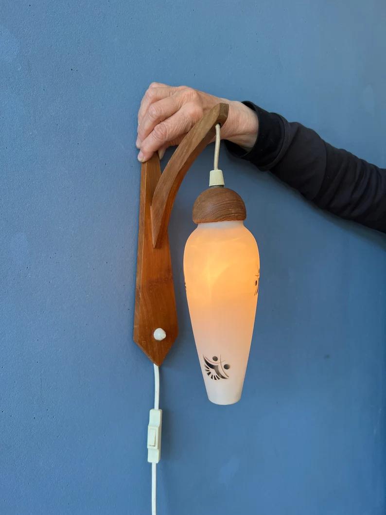 Danish wooden wall lamp with opaline glass shade. The lamp has a switch build into the wall plate. The lamp requires one E27/26 lightbulb and currently has an EU-plug.

Additional information:
Materials: Metal, plastic
Period: 1970s
Dimensions: ø: 7