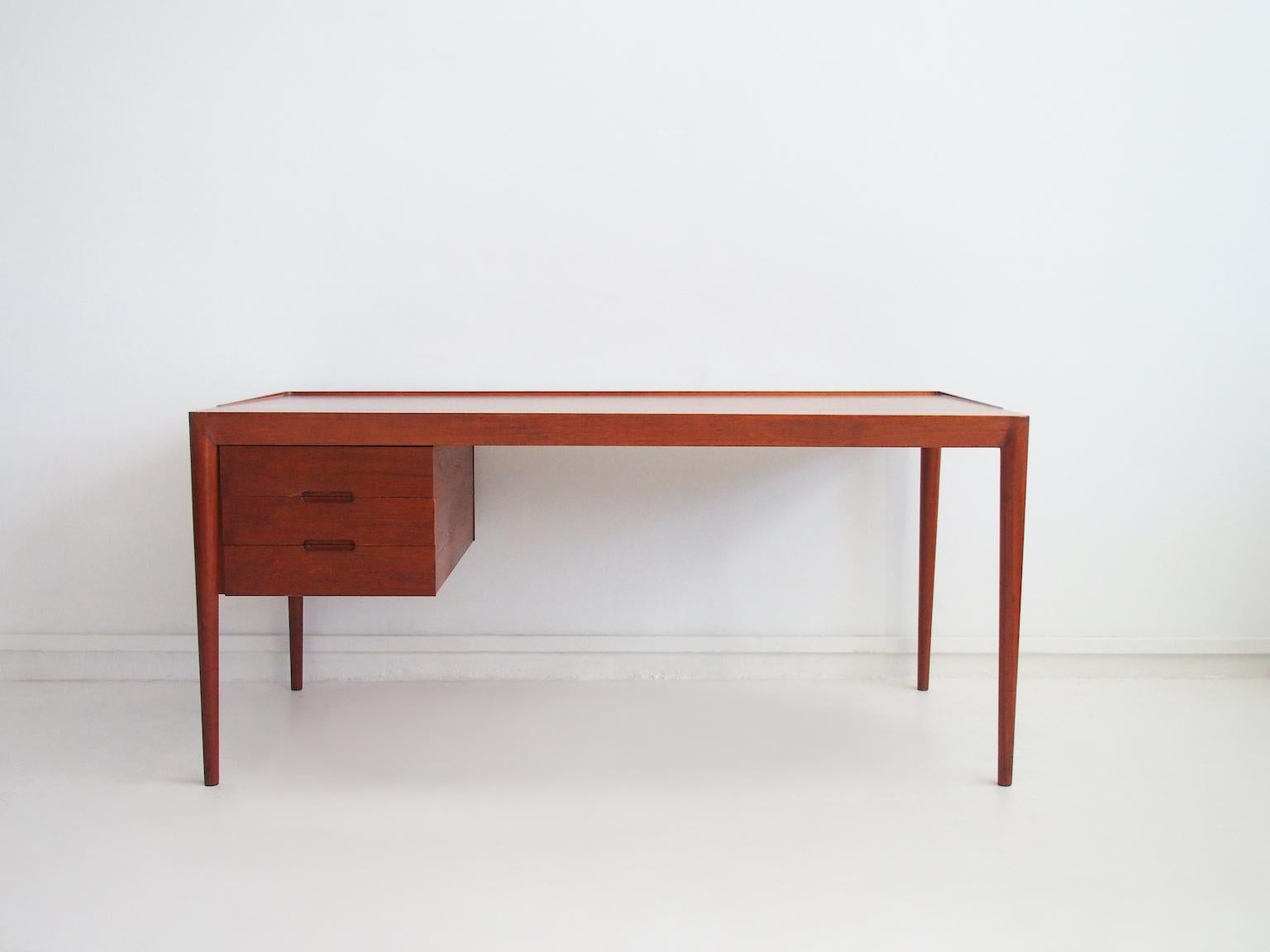 Teak wood desk with scalloped edge on the back. Designed by Erik Riisager Hansen and manufactured by Haslev Møbelsnedkeri, model 66.
Slim tapered legs. Drawer section with three drawers.