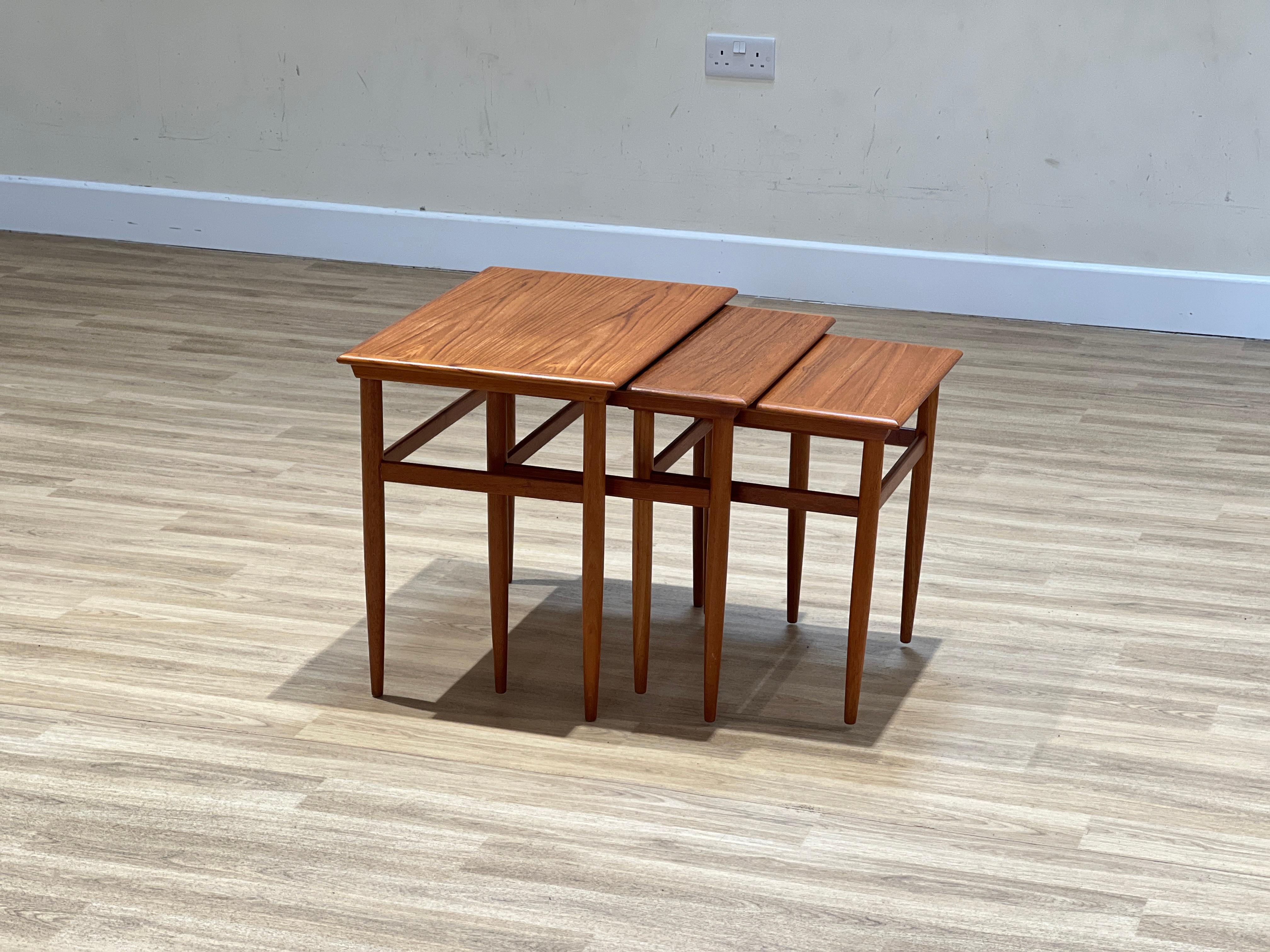 Crafted in Denmark during the 1960s, this striking set of three nesting tables showcases the intricate artistry of Johannes Andersen. Meticulously constructed from stunning teakwood, the tables exhibit the unparalleled craftsmanship of the era. Each