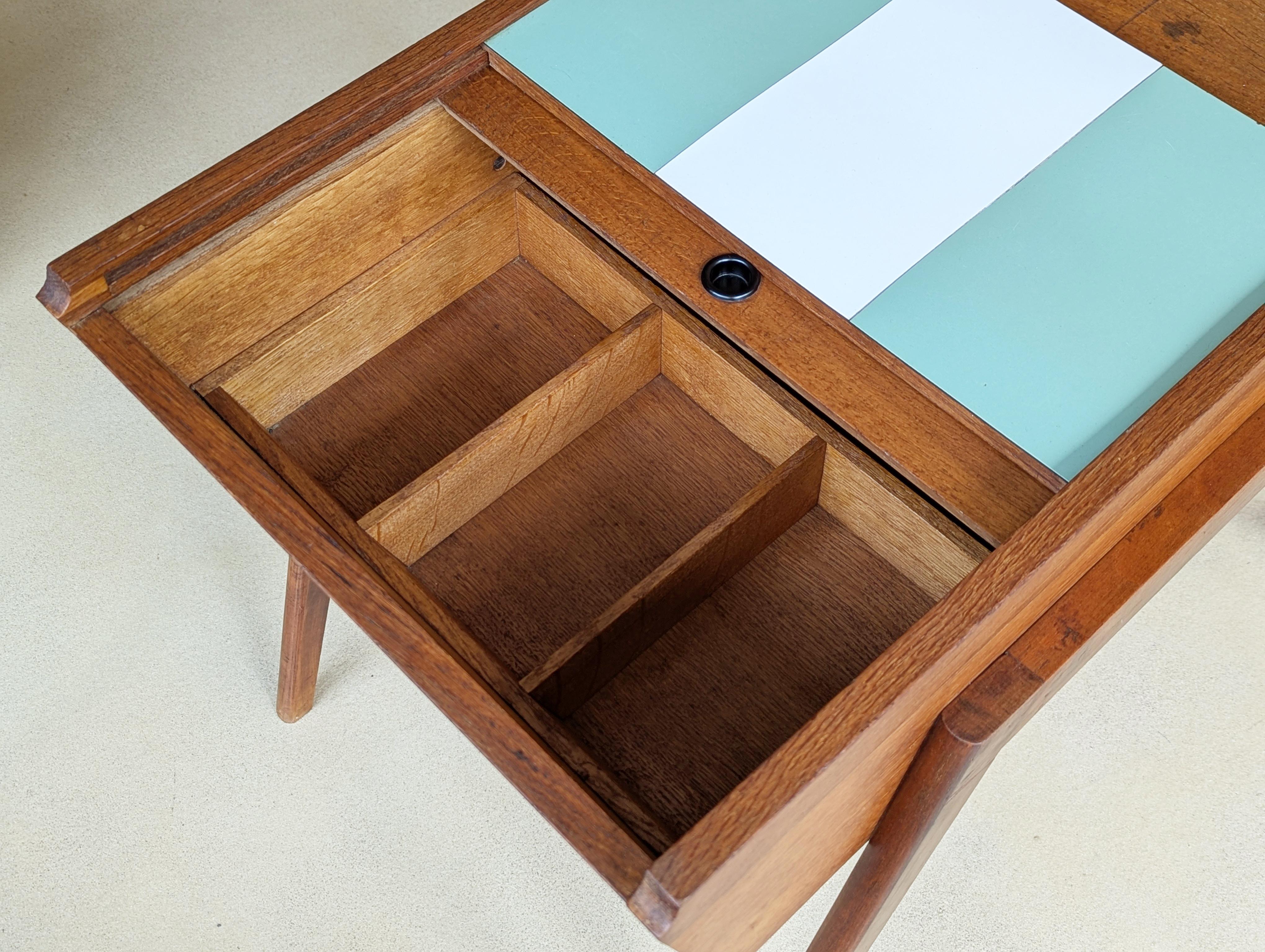 Rare table de travail fabriquée en Italie dans les années 50. Structure en bois de teck avec portes coulissantes recouvertes de stratifié plastique blanc et vert aqua. À l'intérieur du conteneur, des compartiments permettent de rationaliser le