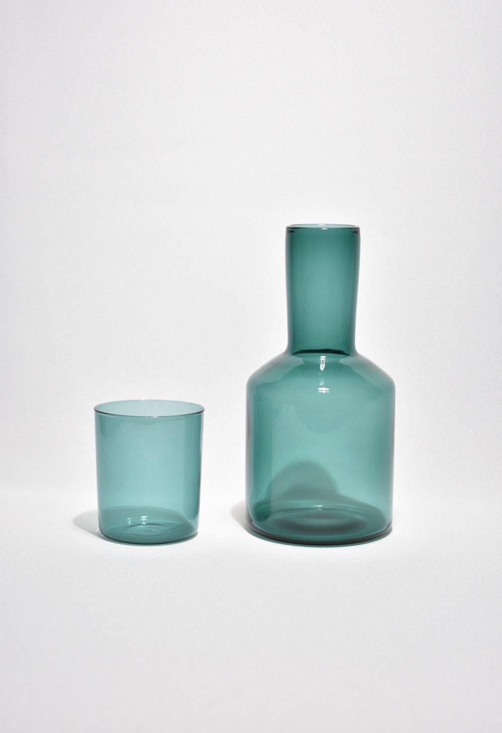Teal carafe set by Maison Balzac inspired by the traditional sets used in France and displayed on a bedside table at night. 

Food grade colored glass, individually mouth blown. 
Heat and cold resistant.
Hand wash