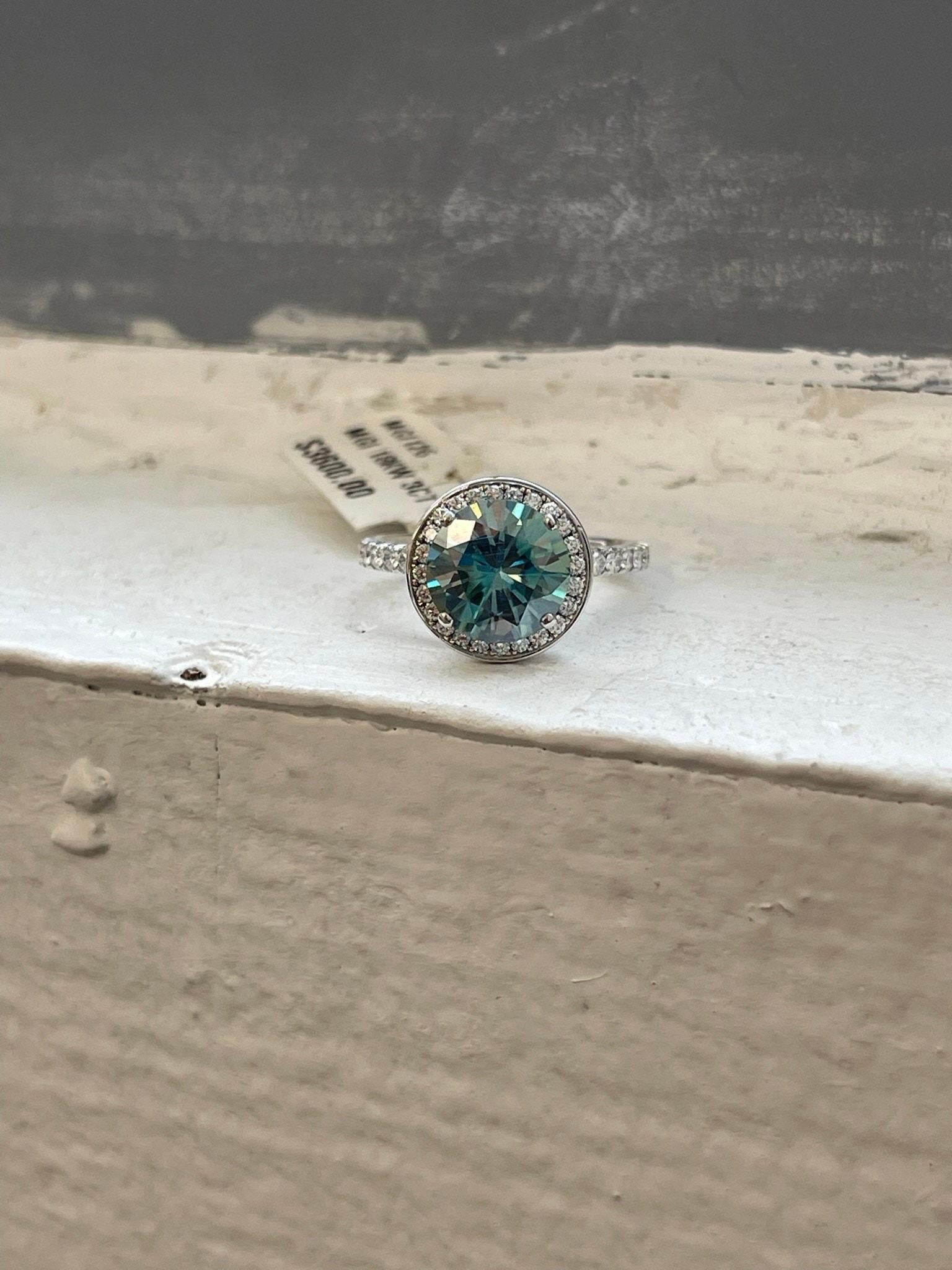 Huge 100mm moissanite with slightly teal blue color accompanied by VS diamonds F color in 18KT white gold in size 5, can be re-sized to any size free of charge. The ring is just so luxurious and so different at the same time!

*Item will come with a