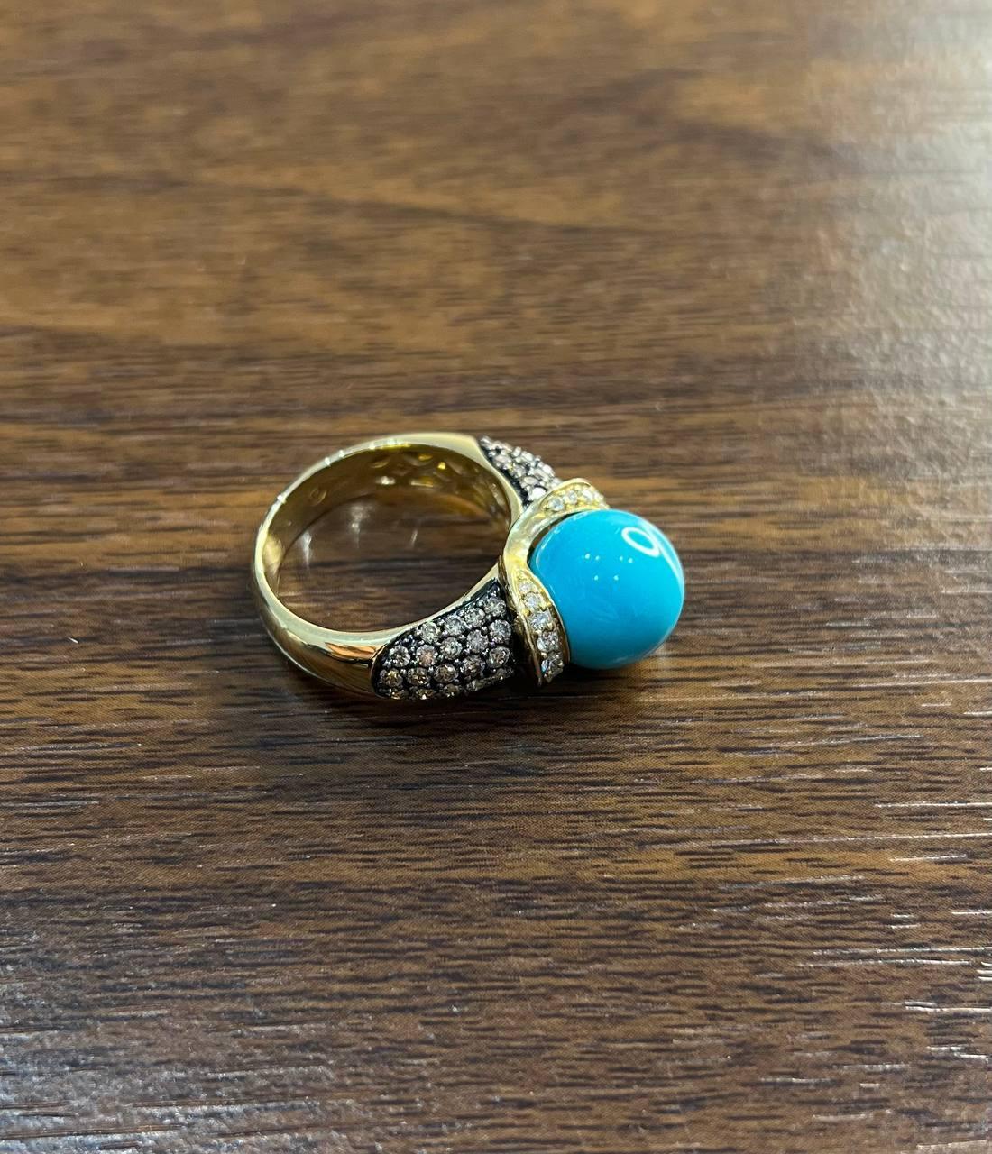 This exquisite multi-stone ring is crafted in 14K yellow gold. It features a striking turquoise cabochon centerpiece, flanked by pavé-set sparkling white diamonds.
The turquoise is smooth and round, creating a bold focal point.
The pavé stones are
