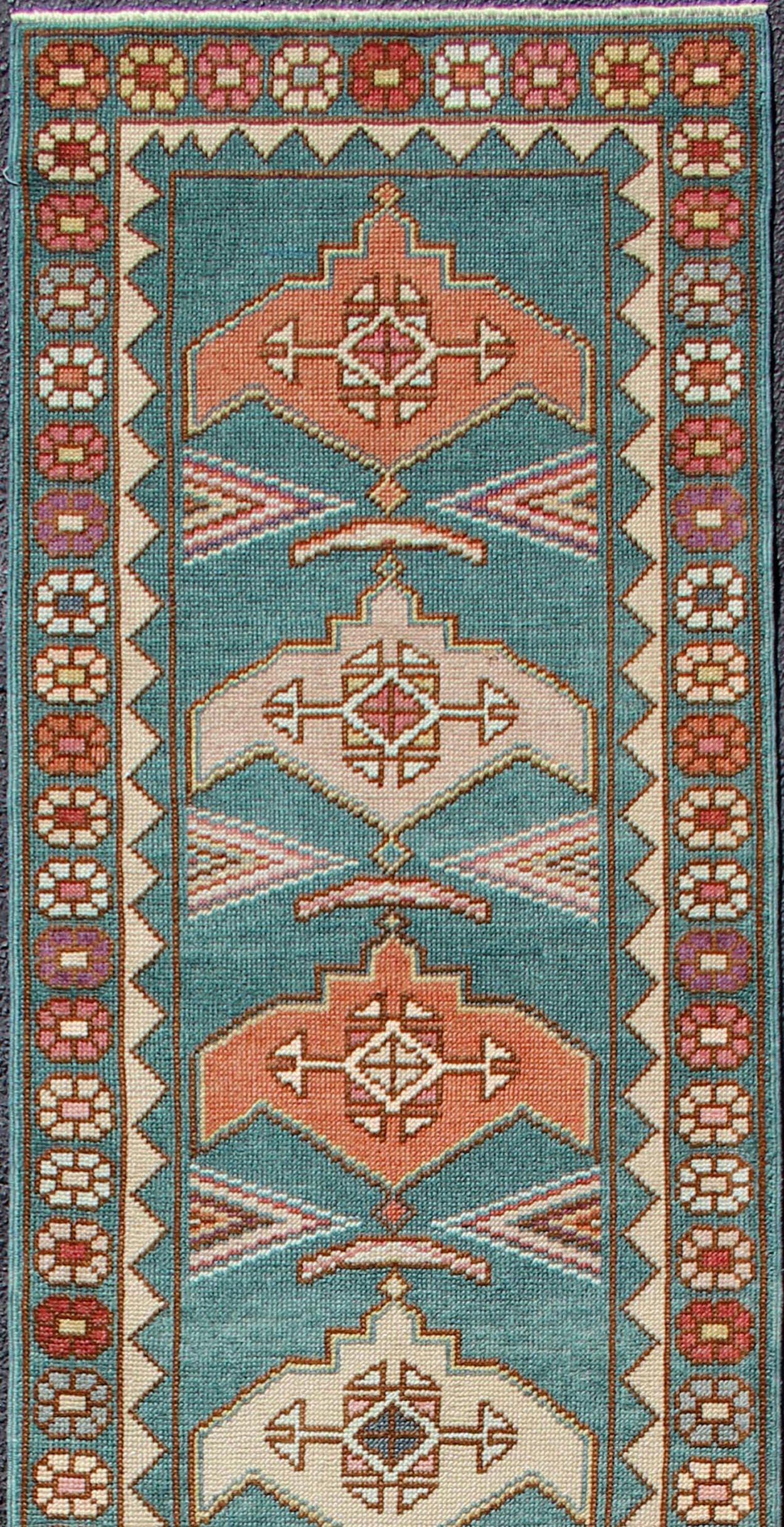Colorful vintage Turkish oushak runner with repeating medallion geometric design in teal color background, rug EN-179682, country of origin / type: Turkey / Oushak, circa 1940

This vintage Oushak runner (circa mid-20th century) features a unique