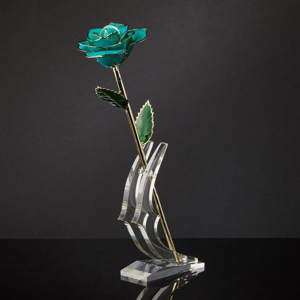 Meaning Behind The Rose. Put a little fun and whimsy into someone’s day with our Teal Rhapsody Eternal Rose. Showcase your deep feeling with this beautiful teal rosebud, surrounded by dark green leaves with gold accents. The stem is strong and