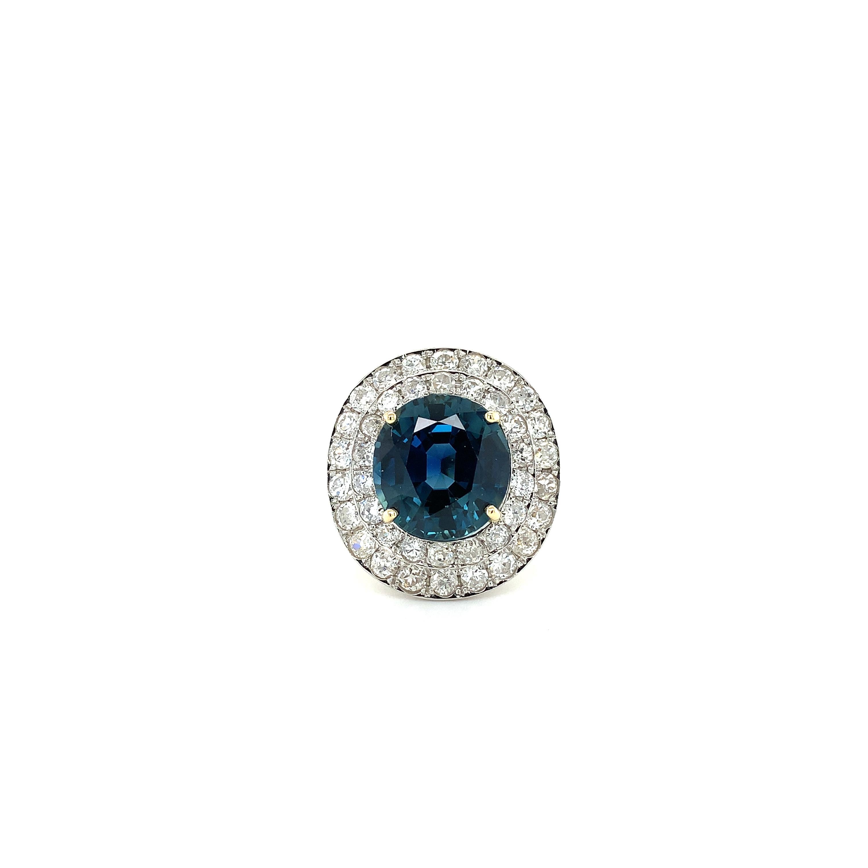 This stunning 18k yellow gold cocktail ring features a gorgeous teal sapphire natural clear as its centerpiece unheated comes with certificate cushion shape weighing 9.50ct surrounded by sparkling double halo diamonds weighing 2.10ct F-VS1. Size M.