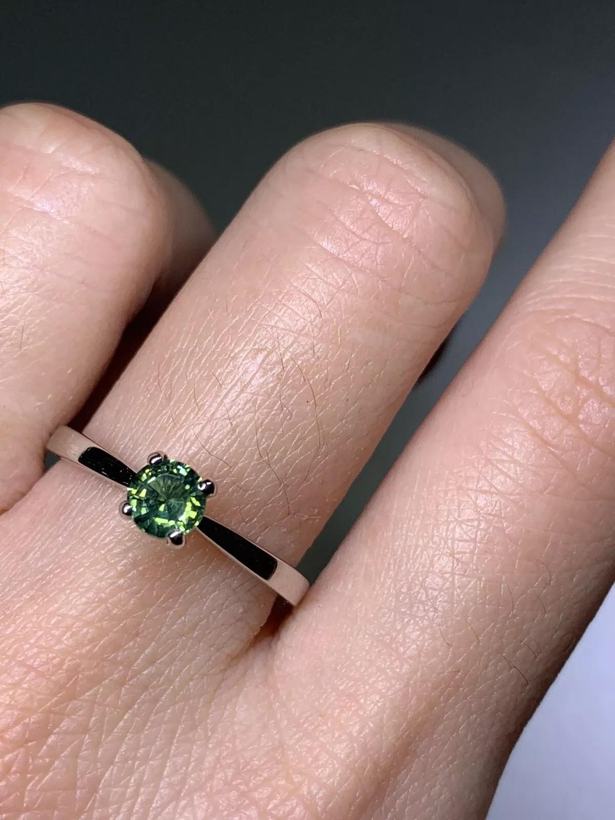 Teal sapphire gemstone solitaire ring in 18ct white gold, natural gemstone round cut plain band.
The ring can be resized.
Box and valuation included.
Hallmarked.
Elevate your engagement with this stunning 0.65ct Teal Sapphire Solitaire Ring. Crafted