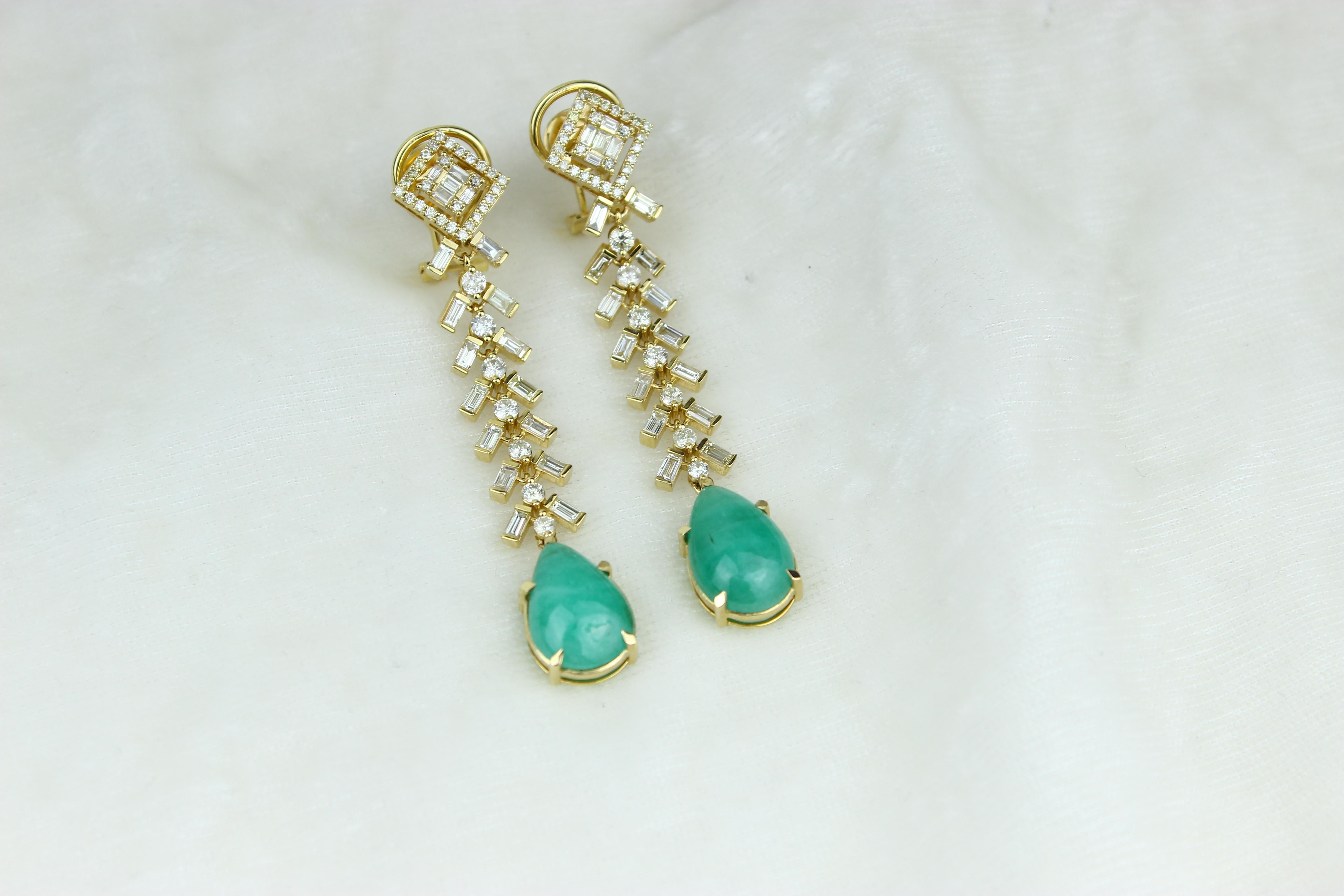 These Tear Drop Emerald Gemstone and Diamond Earrings feature high-quality emerald gemstones set in 18K solid gold and are adorned by baguettes and round diamonds. The elegant dangle drop style adds movement and dimension to the earrings, making